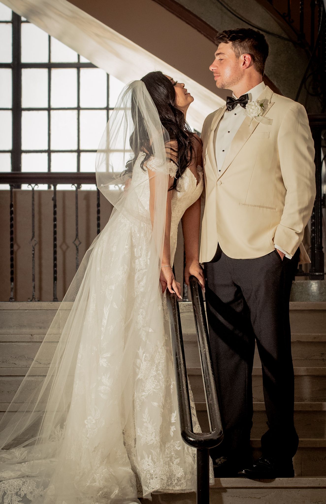 Romantic wedding portrait of couple in elegant attire on vintage staircase.