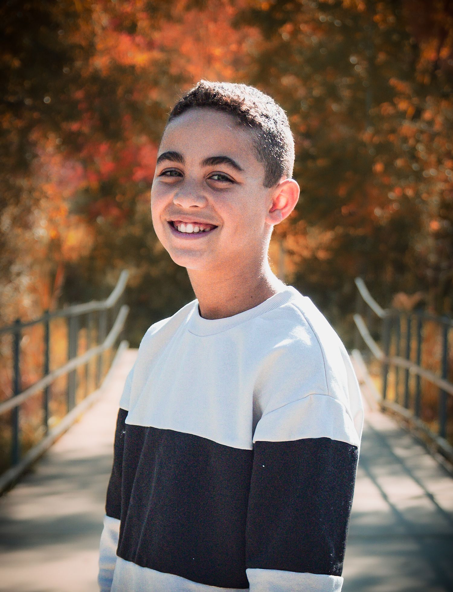 A person in a black and white top smiling outdoors during autumn.