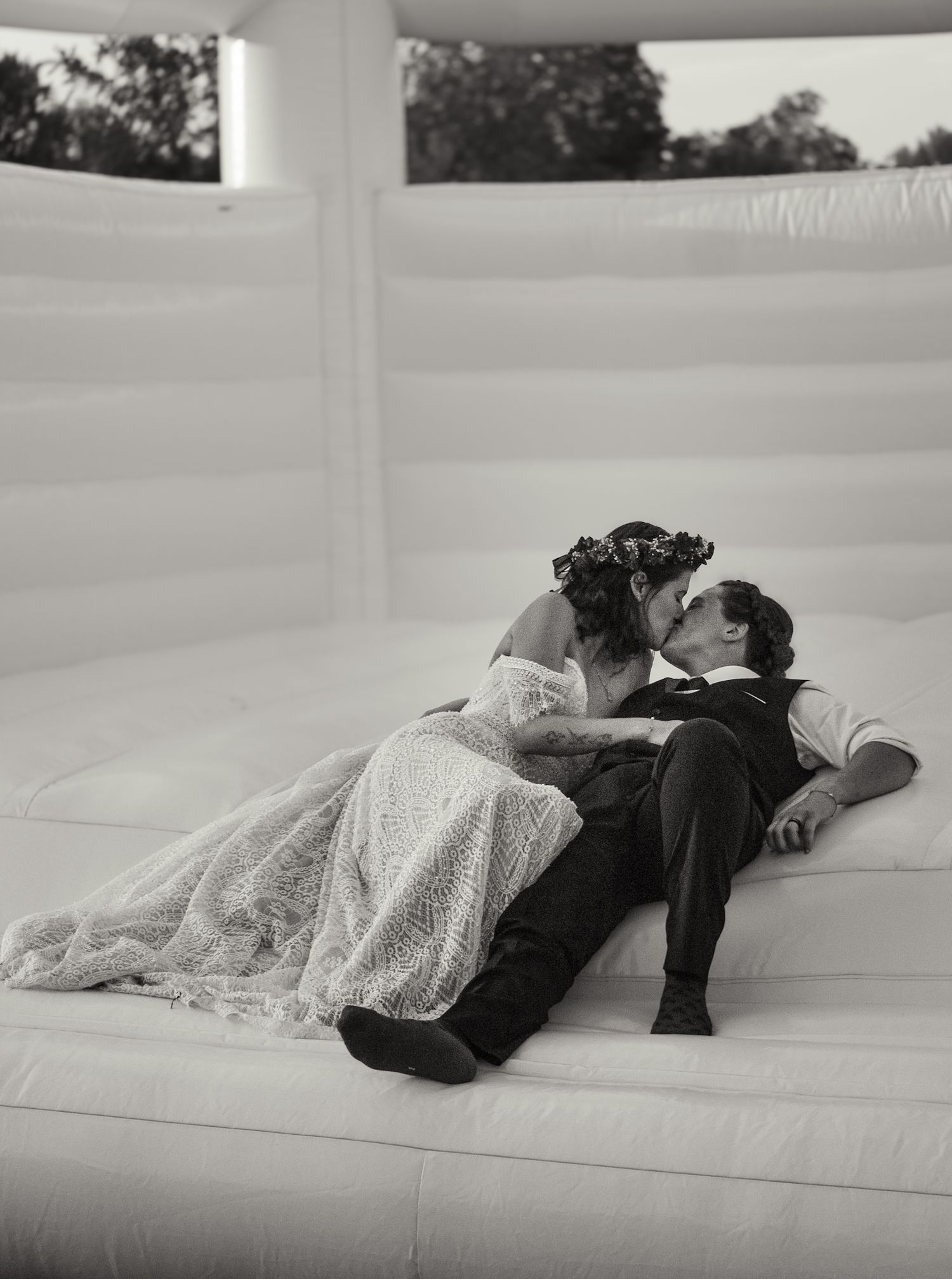Black and white series of couple lying together on white surface in wedding attire.