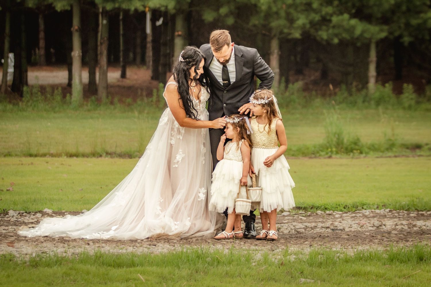 A wedding scene with a couple and child in formal attire standing together on a grassy field.