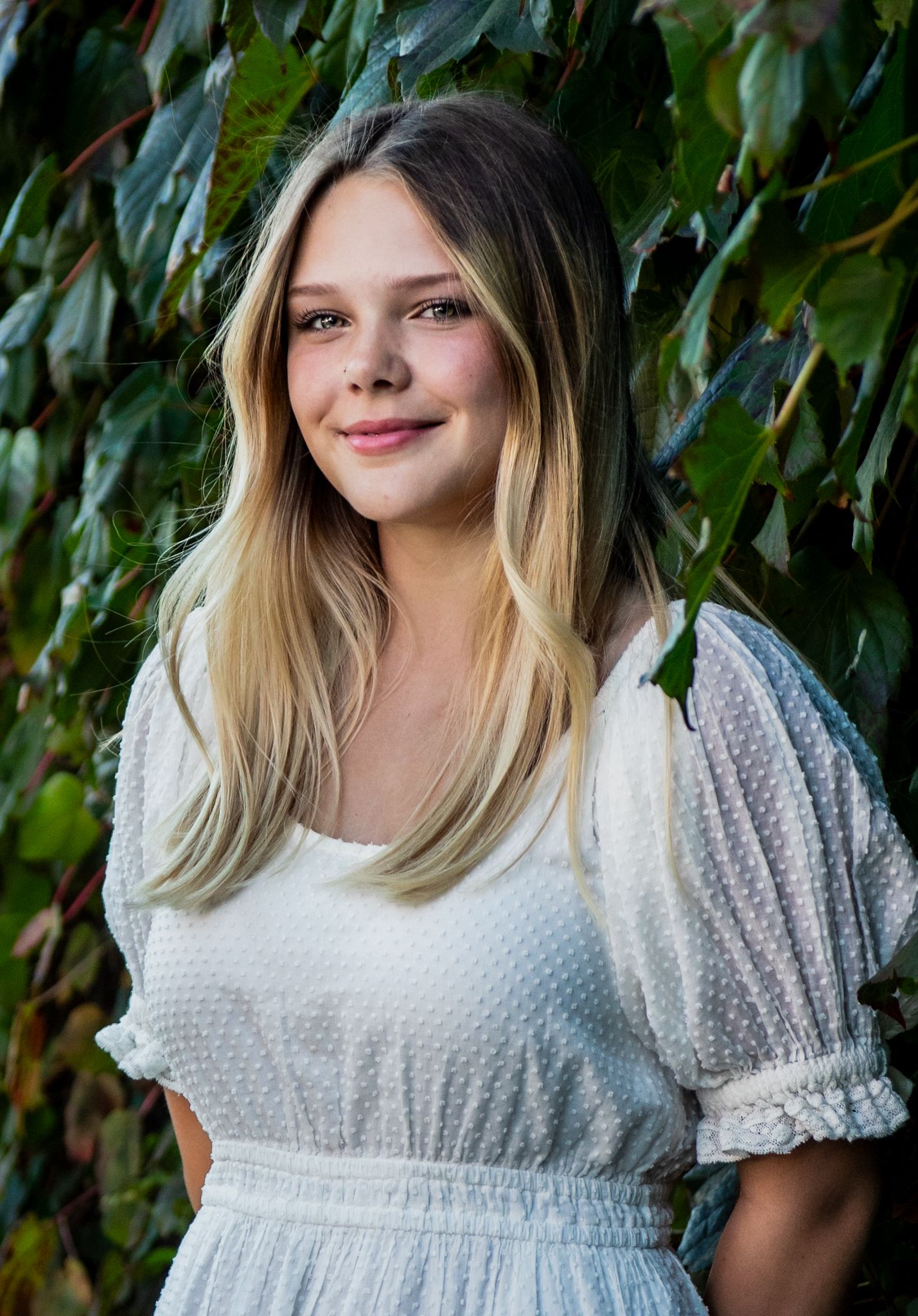 Portrait series of someone in a white textured dress against green foliage.