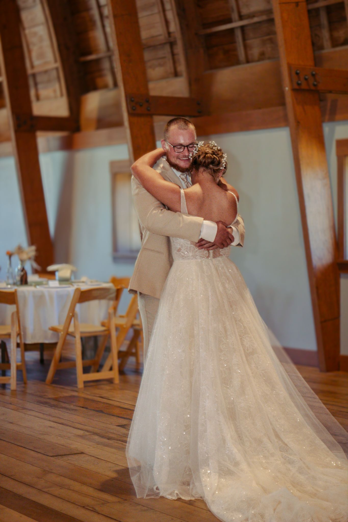 Couple sharing an intimate first dance in a rustic wooden barn venue with sparkling white dress at The Cathedral Barn in Traverse City MI