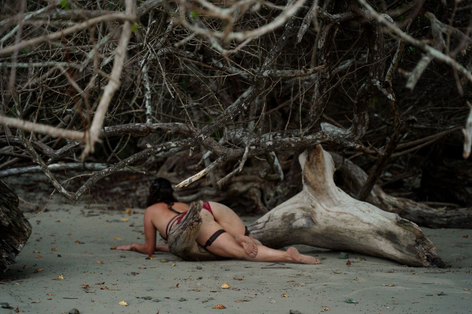 Person relaxing on sandy beach next to driftwood log in artistic beach photography.
