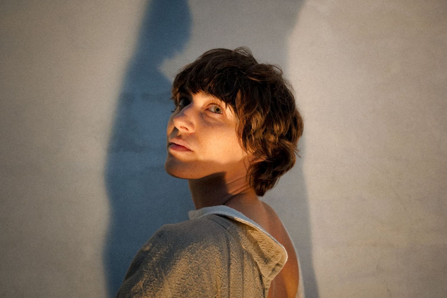 Portrait with dramatic lighting and shadow against a plain wall.