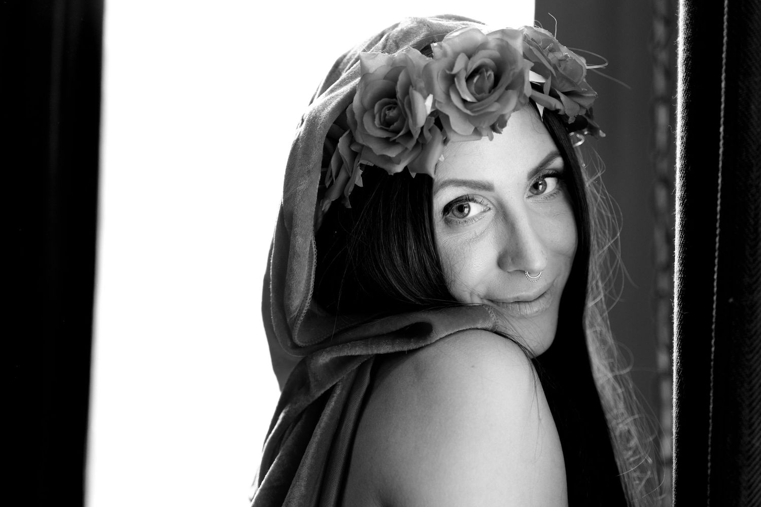 Dramatic portrait with floral crown and dark fabric in monochrome style.