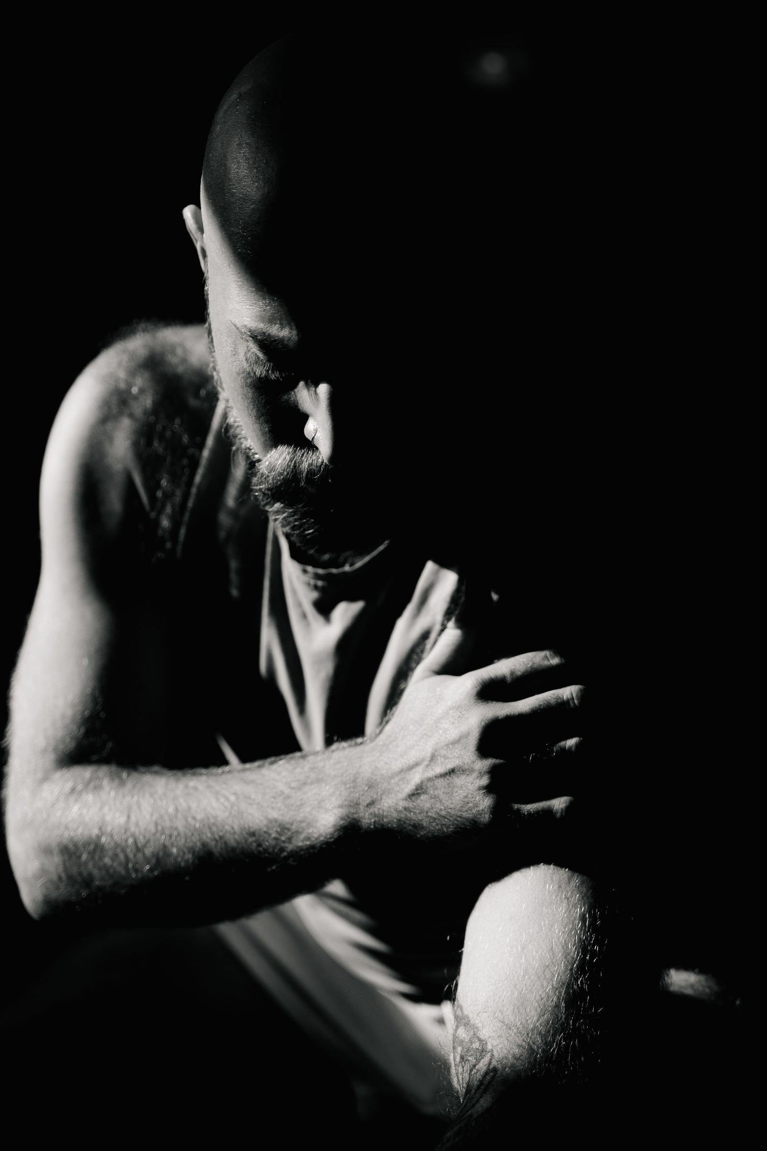 Dramatic black and white portrait of person in deep contemplation against dark background.