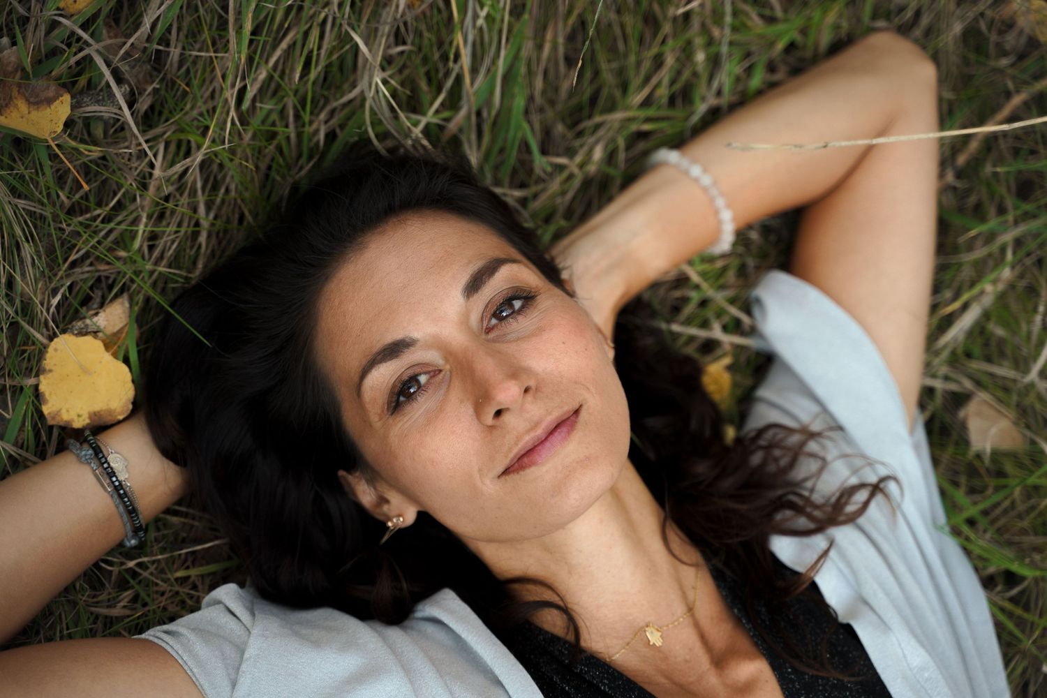 A relaxed summer portrait of someone lying in tall grass with yellow flowers.