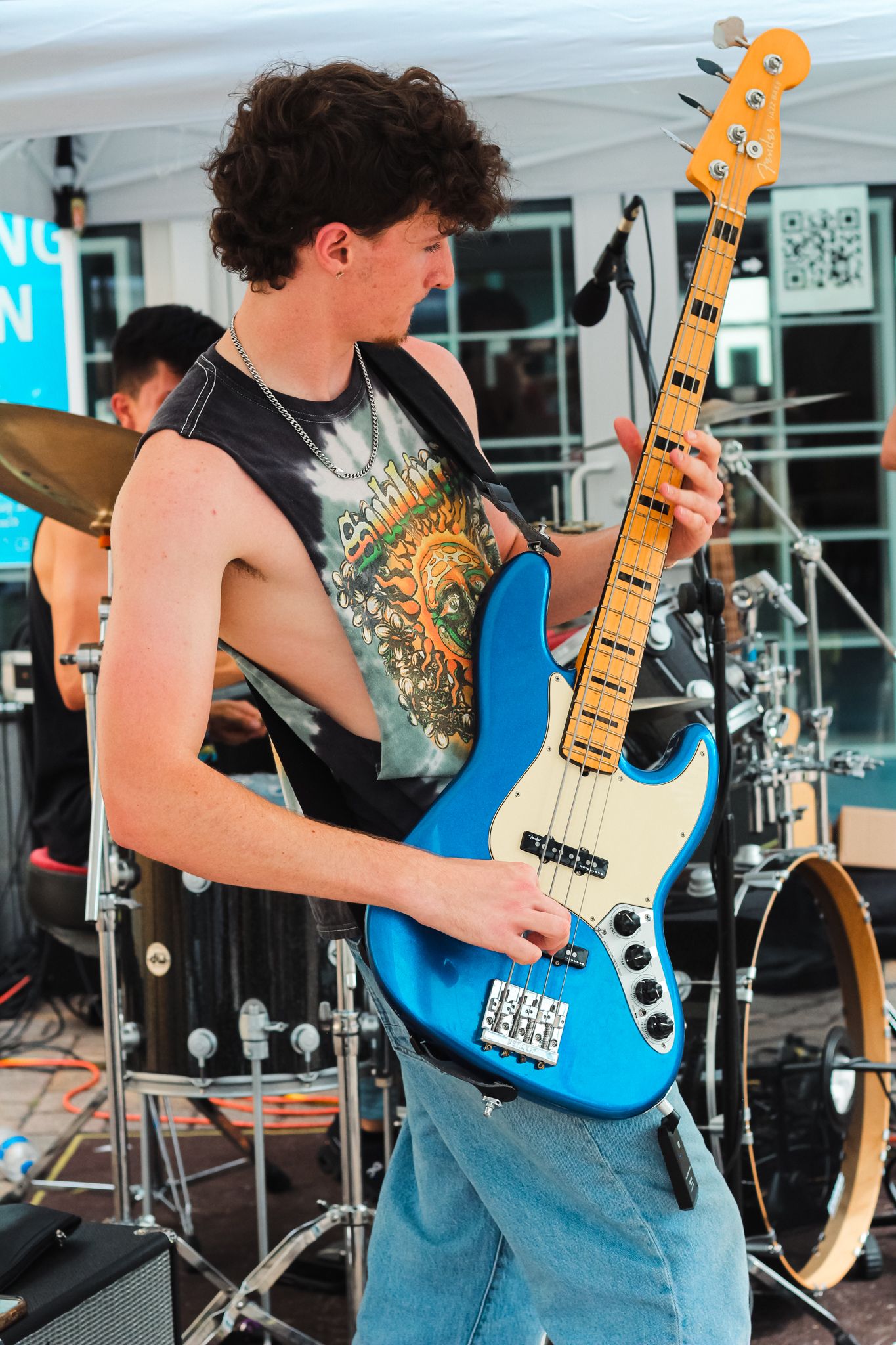 A dynamic live-performance shot of Brendan Mcintosh a local musician  playing an electric bass guitar on an outdoor stage.