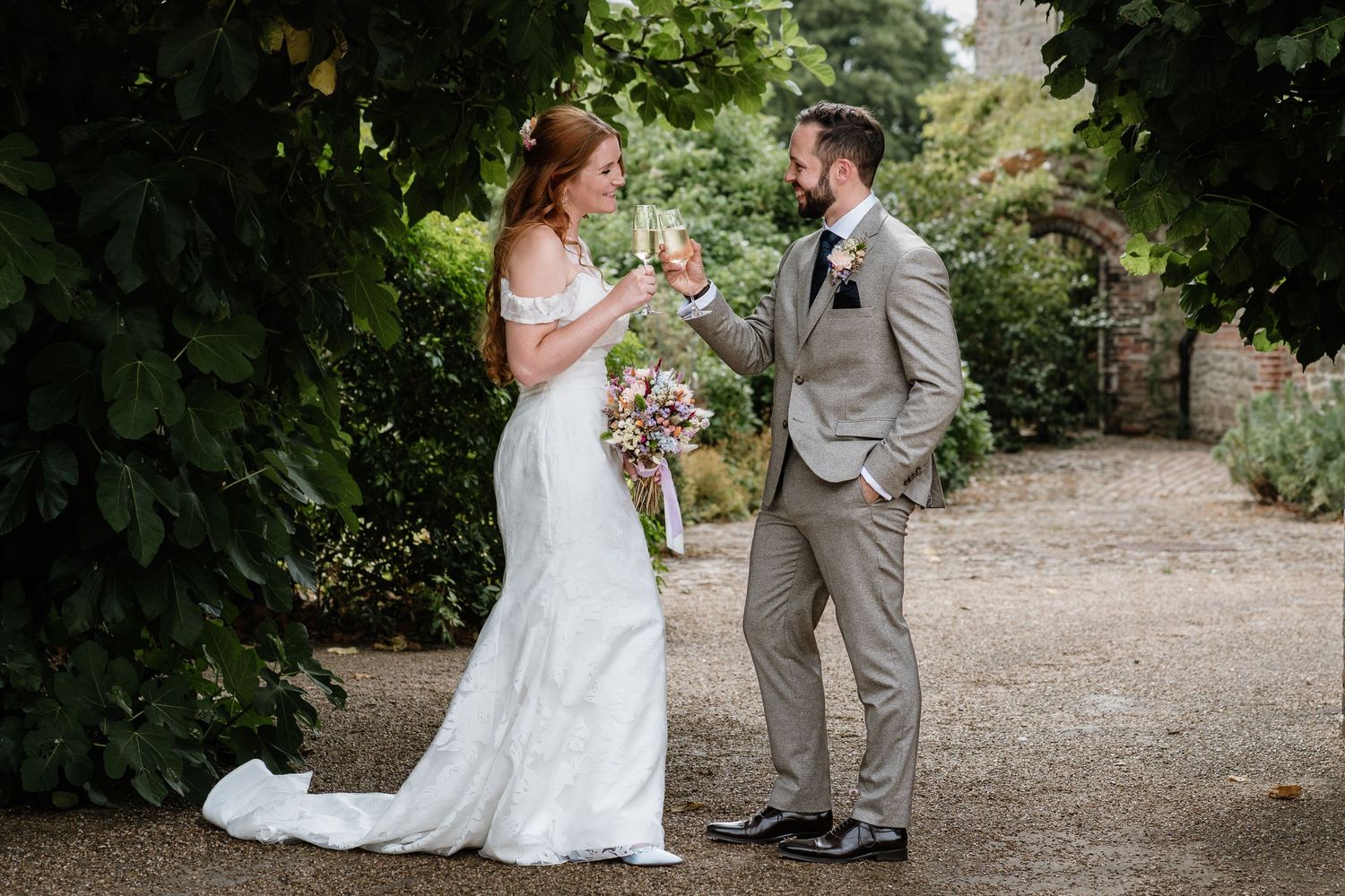 Bride and groom sharing a relaxed moment together on a garden pathway.