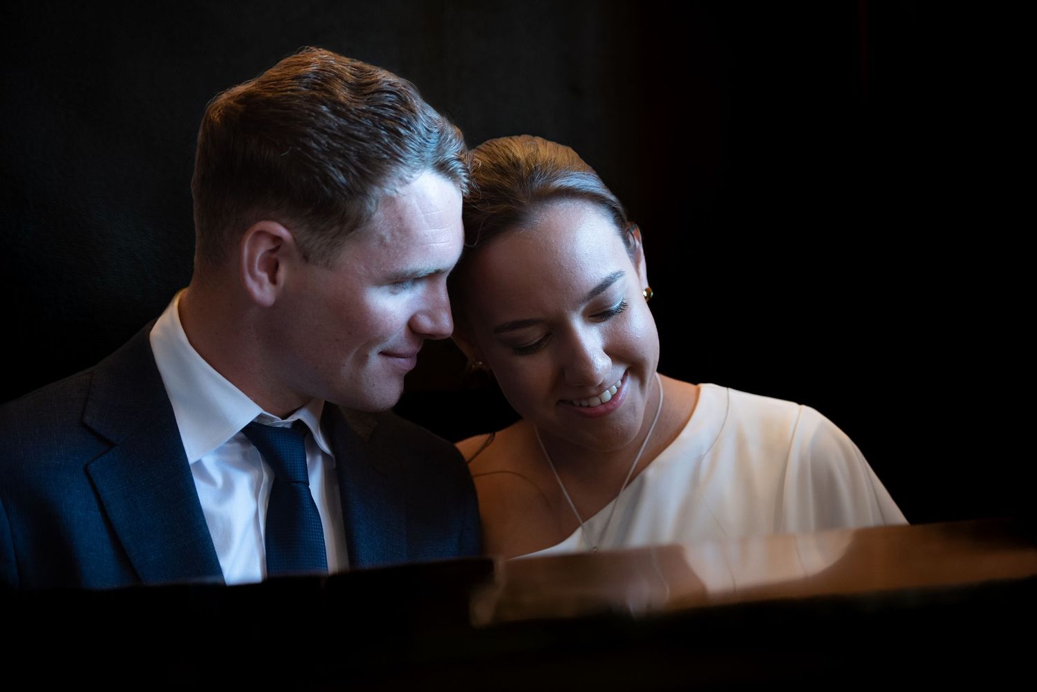 Intimate wedding photograph of a bride and groom sharing a quiet moment together in soft, dramatic light.
