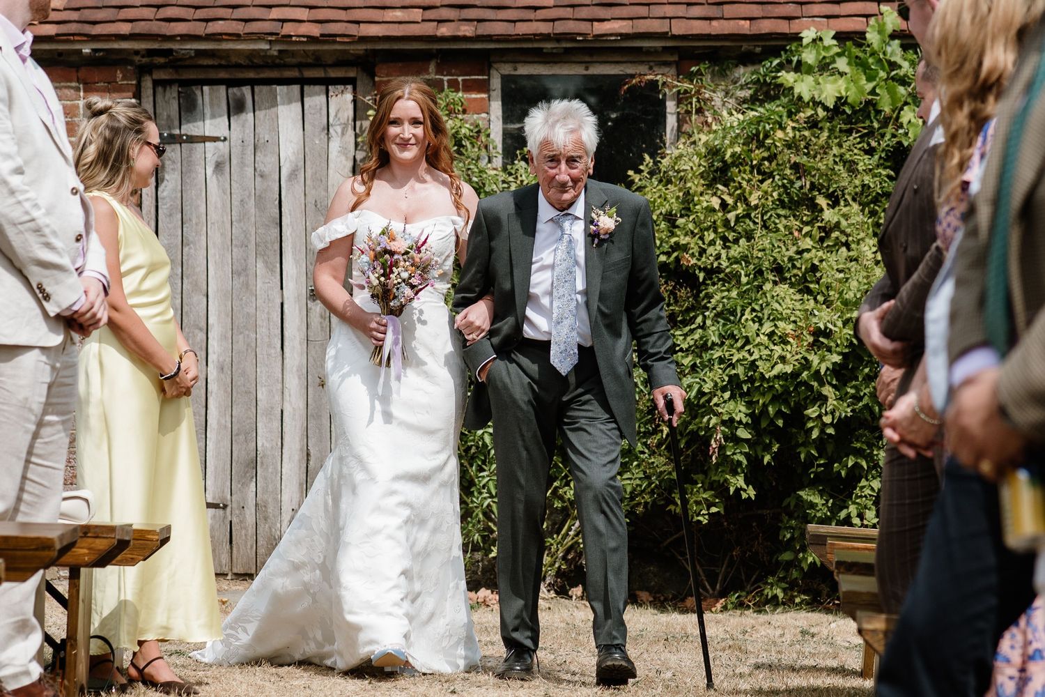Bride walking arm in arm with an her dad during an outdoor wedding celebration.