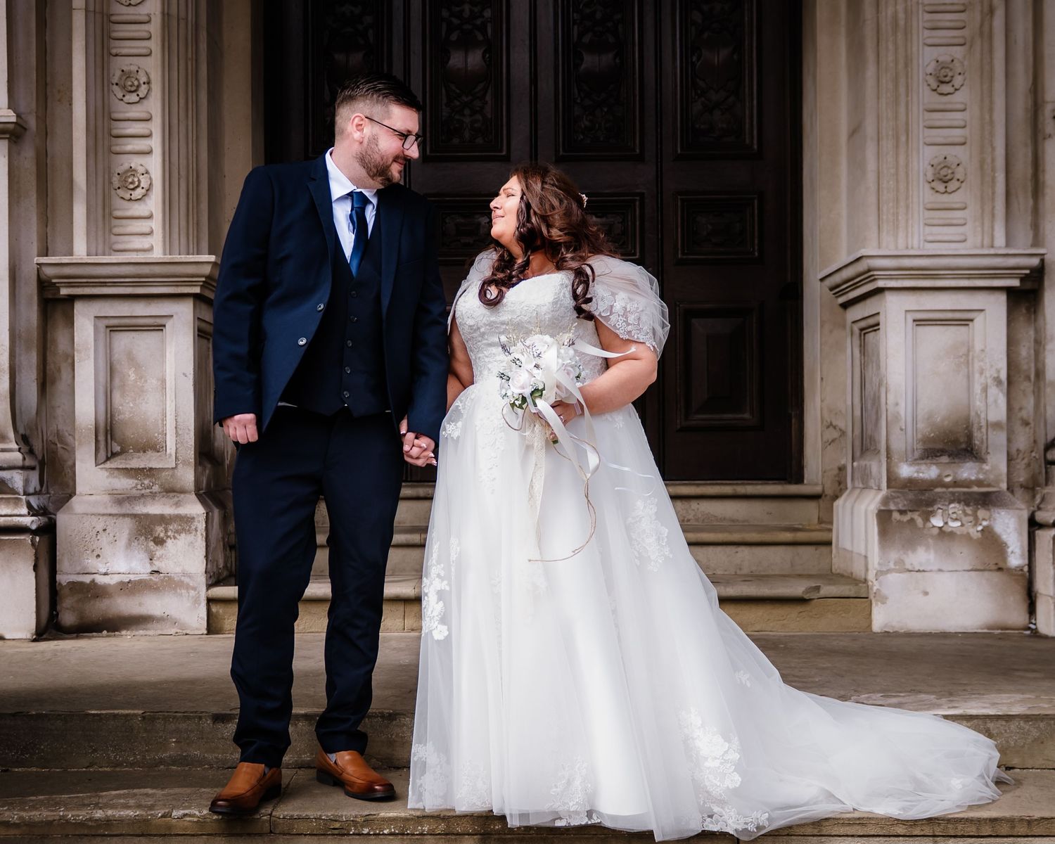 Bride and groom sharing a quiet moment together outside an elegant historic building.