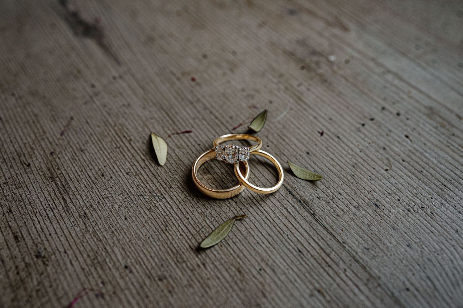Close-up of two gold wedding rings arranged on a rustic wooden surface.