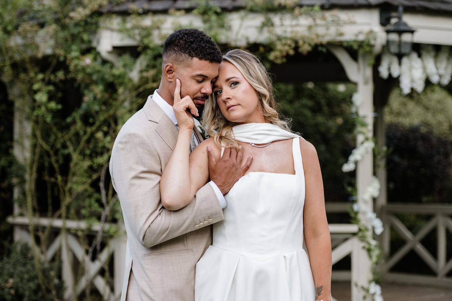 Intimate wedding portrait of a bride and groom embracing in a garden.