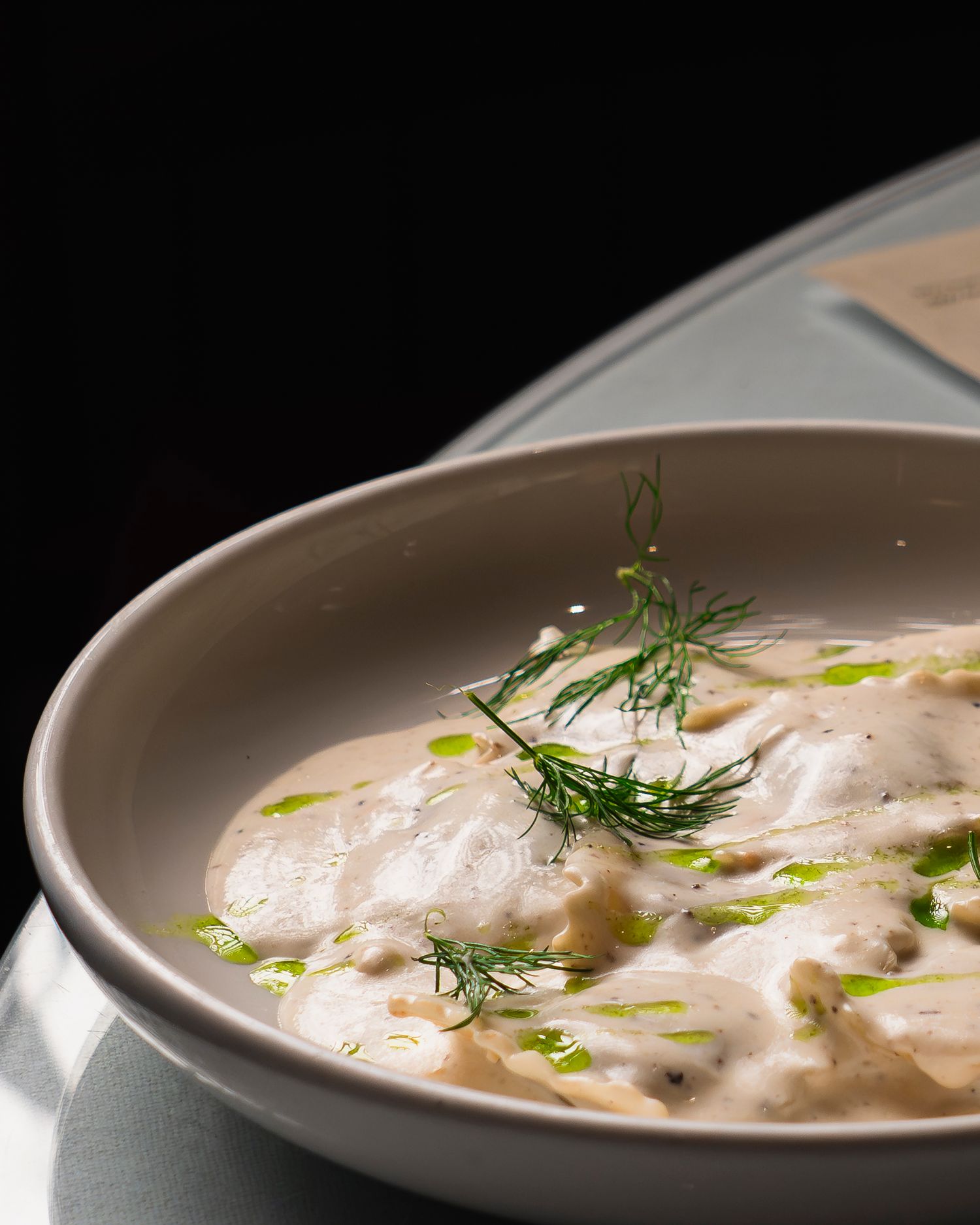 A creamy mushroom soup garnished with fresh dill in a white ceramic bowl.