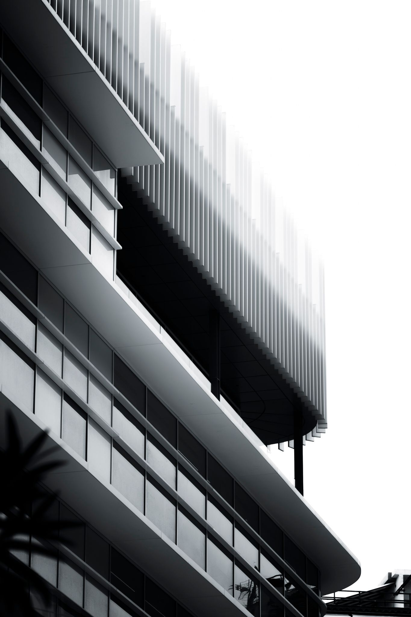 Modern black and white architectural building facade with vertical fins and curved balconies.