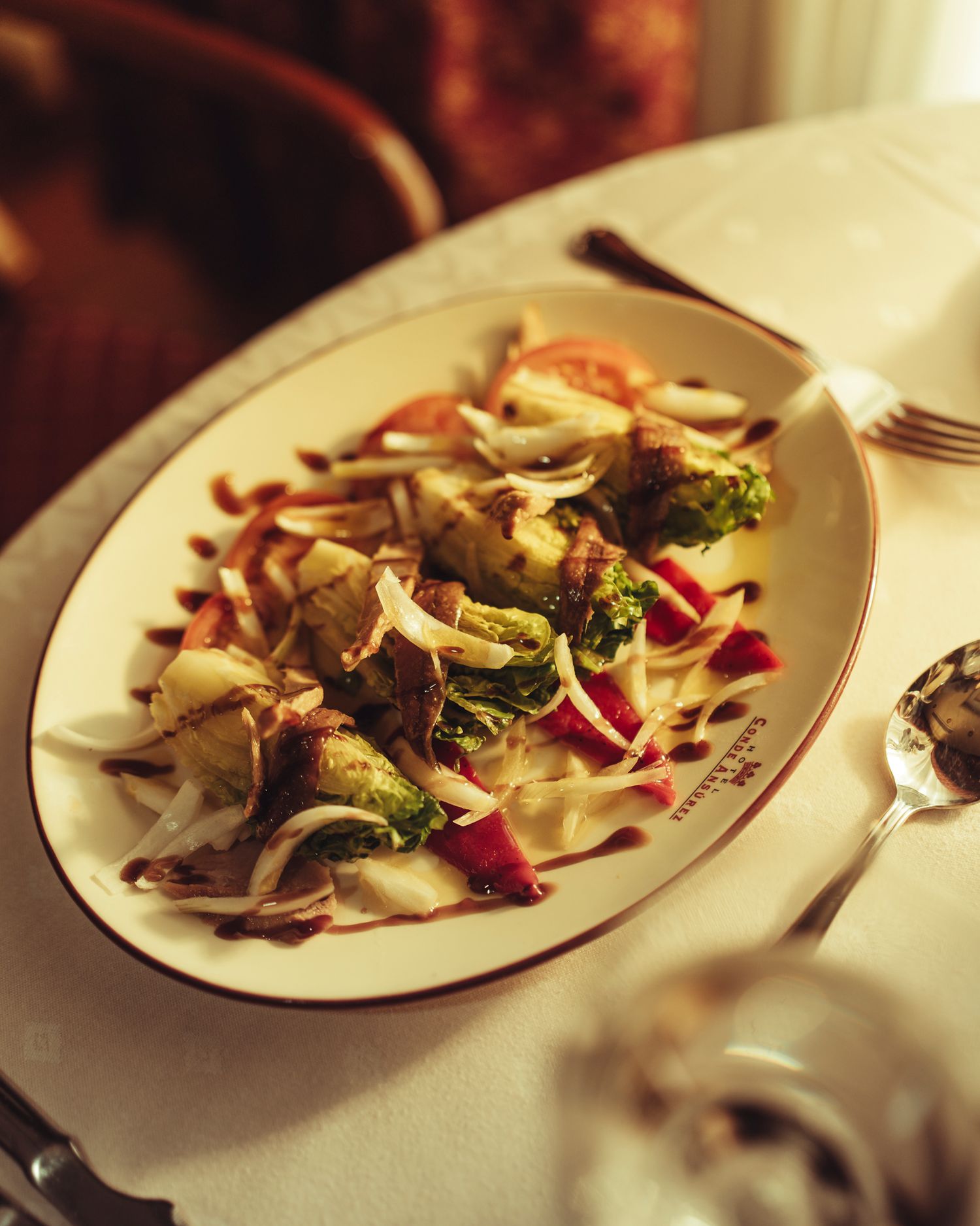 Roasted Brussels sprouts and vegetables with balsamic drizzle served on an oval white plate with red trim.