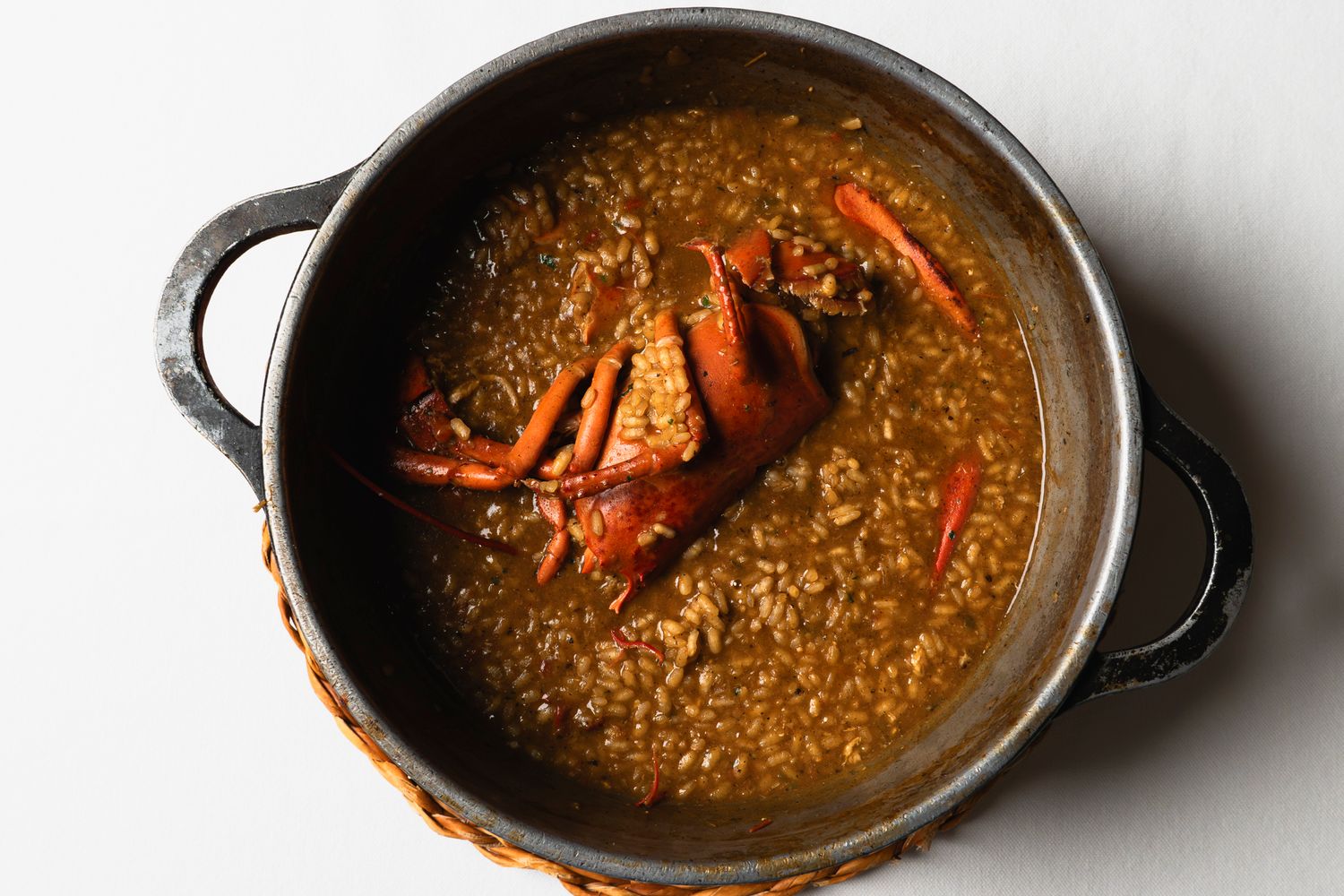 A dark pot of rich crab gumbo stew with a whole crab on top, served in a rustic cast iron pan.