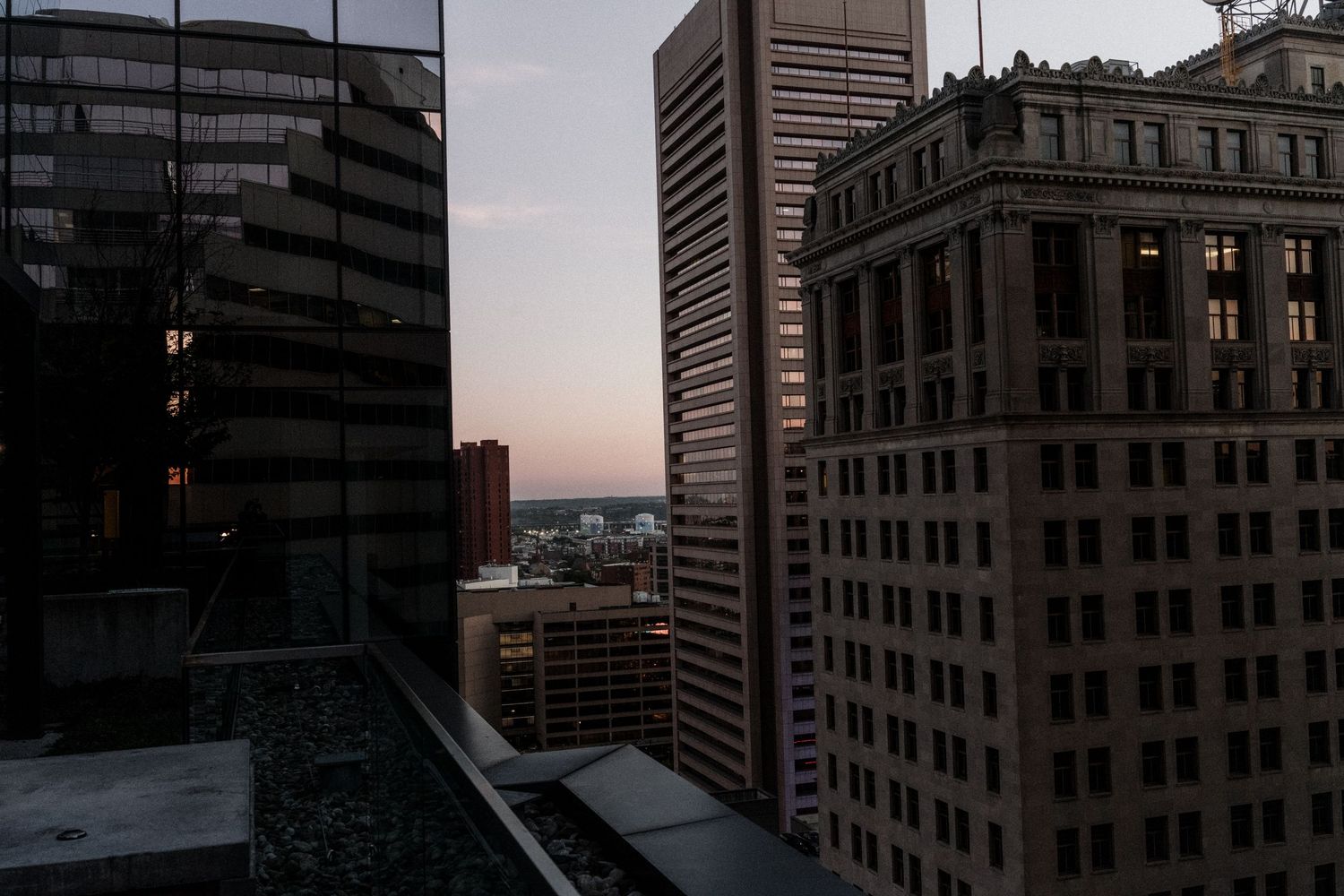 Aerial dusk view of downtown city skyscrapers with glass and stone facades against a twilight sky.