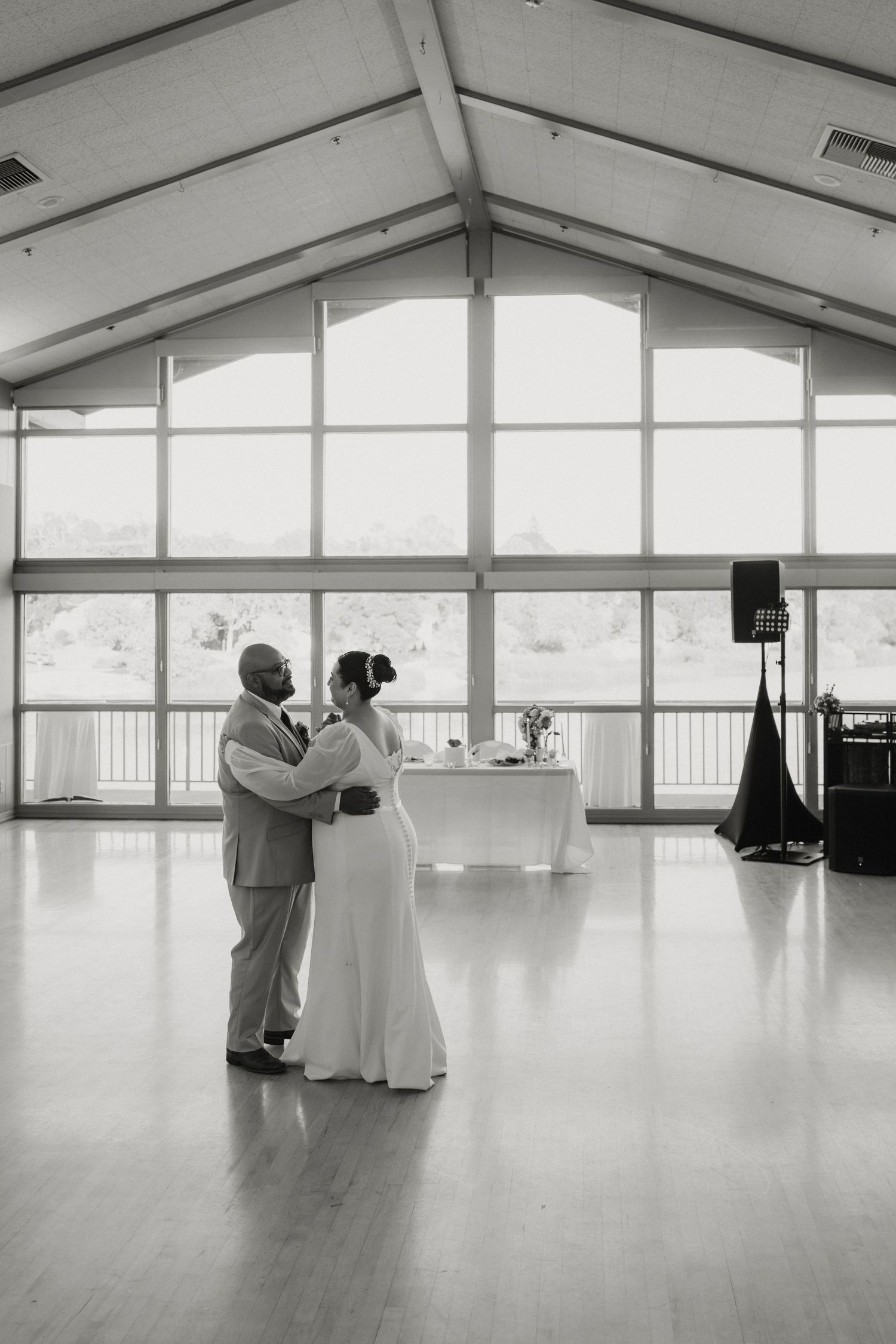 Black and white photo of bride and groom sharing romantic first dance in elegant venue.