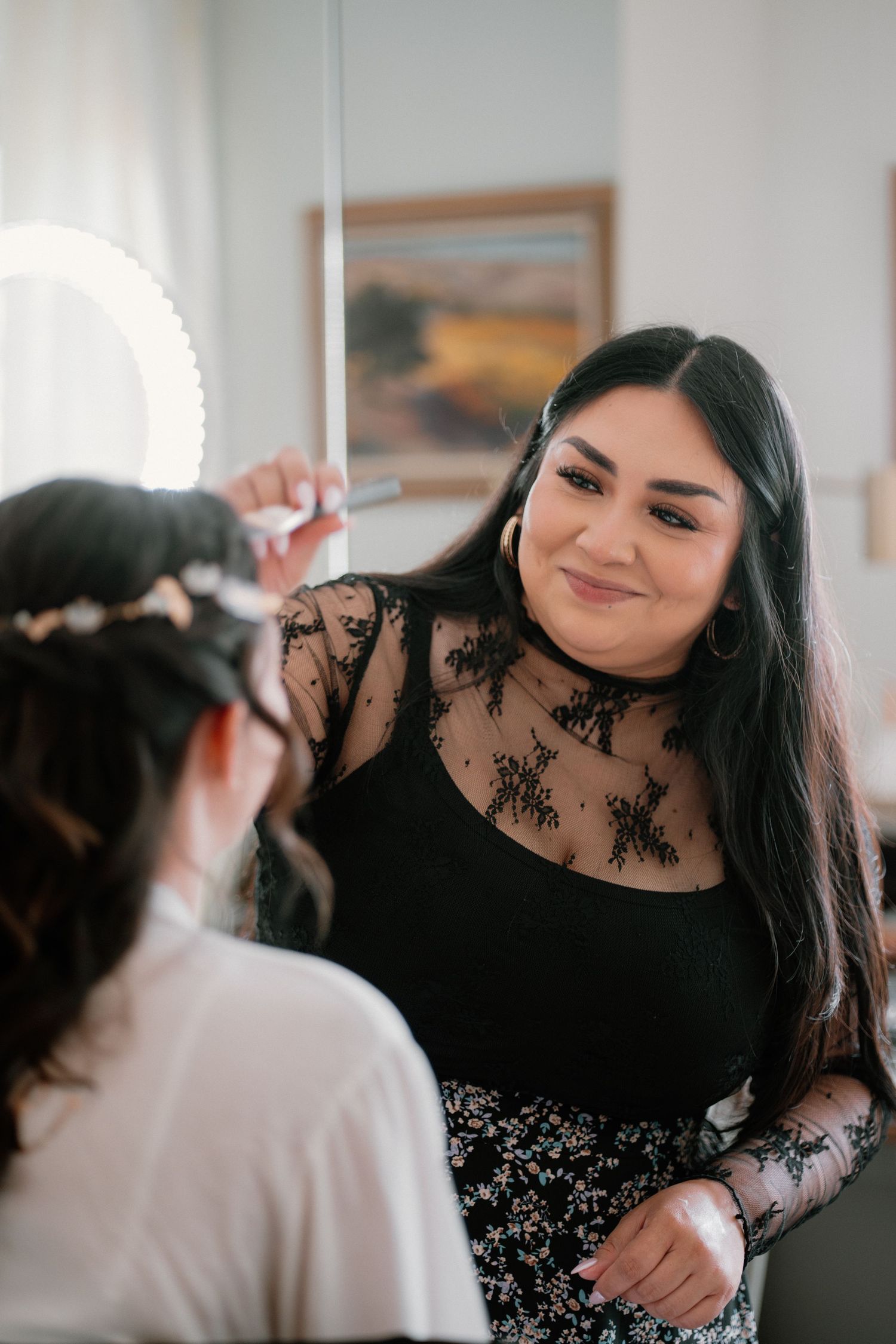 A makeup artist applies finishing touches to a bride with a floral hair crown before her wedding.