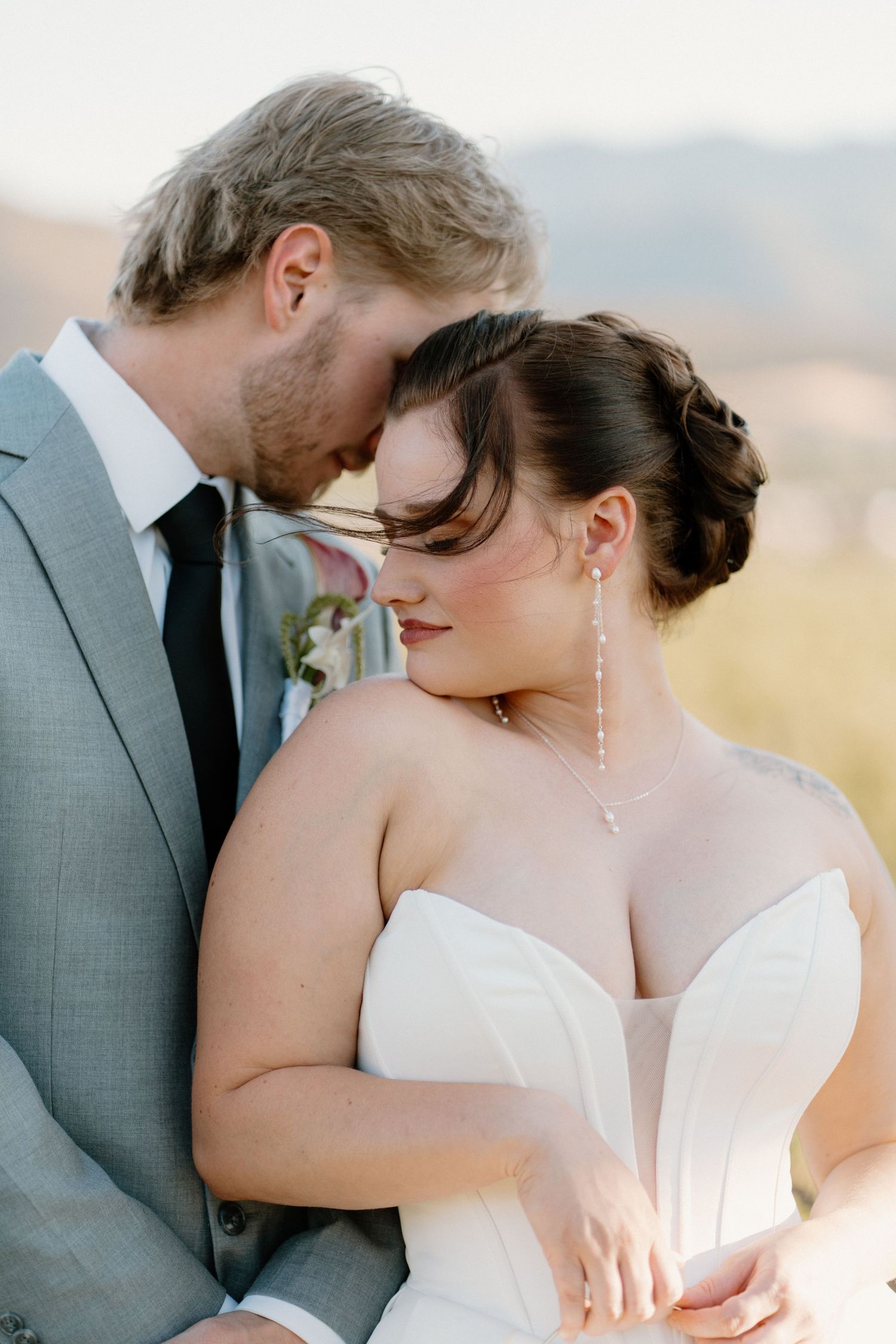 Groom tenderly rests his forehead against his bride in an intimate wedding portrait with mountain views.
