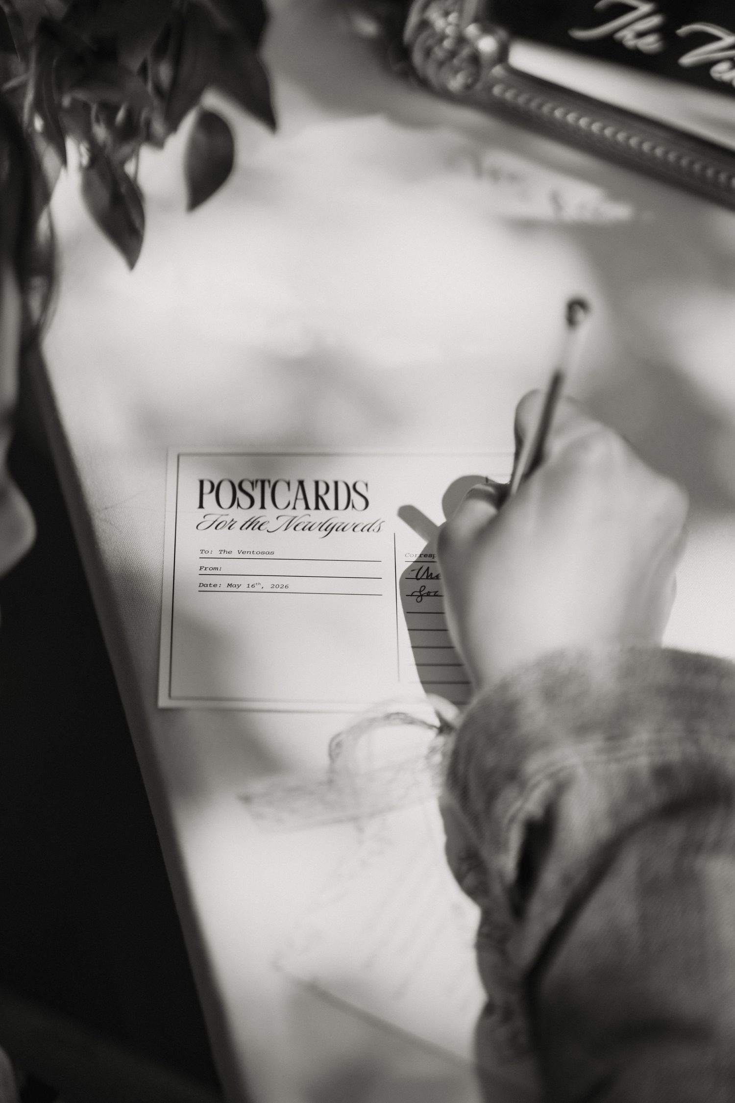 Guest writing a message on a postcard for the newlyweds at a wedding reception guest book table.