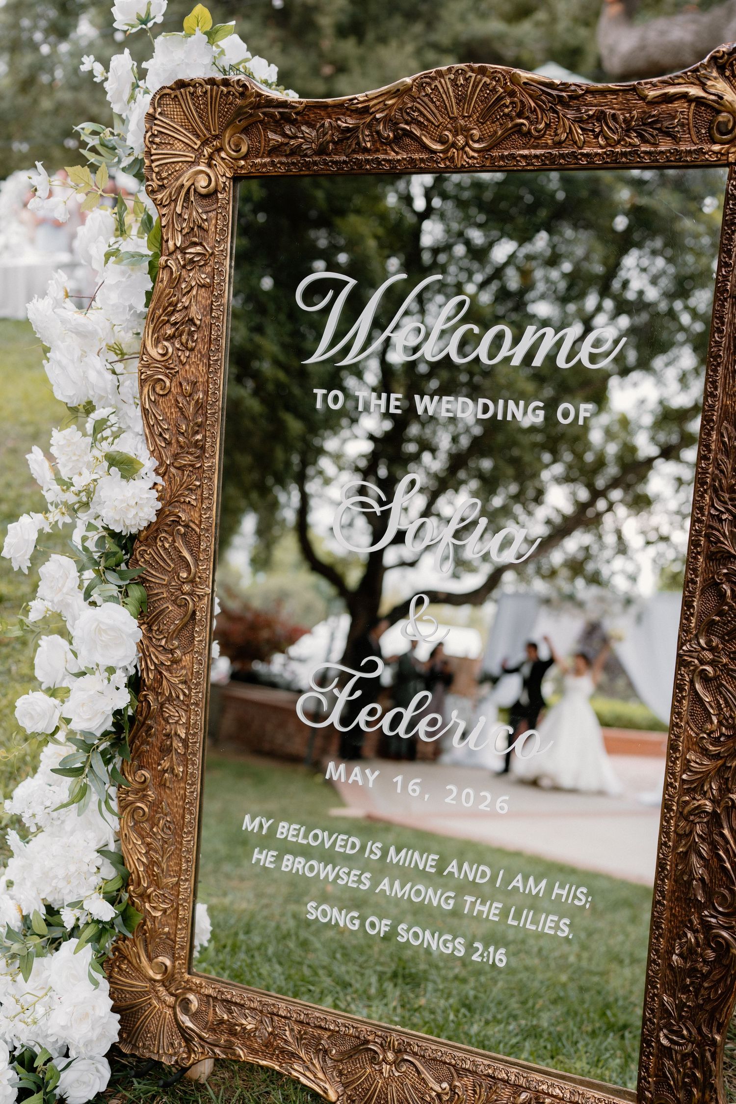 Gold ornate mirror wedding welcome sign for Sofia and Federico, May 16, 2025, with white florals.