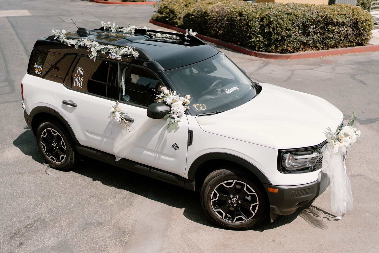 White Land Rover SUV decorated with white floral wedding ribbons and bows for a wedding getaway car.
