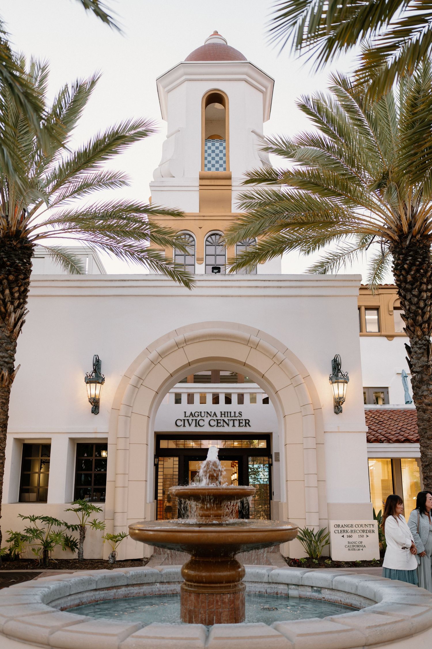 Laguna Hills Civic Center entrance with fountain and palm trees at dusk.