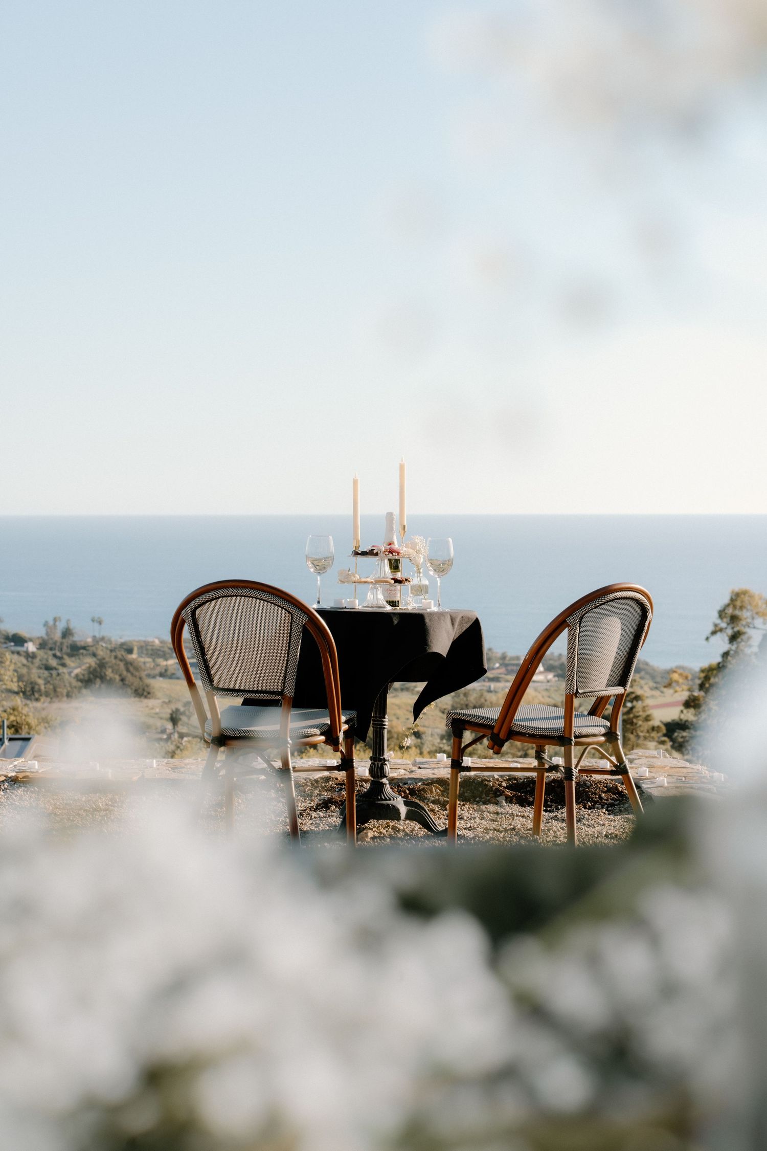 Romantic oceanview table set for two with candles and wine glasses for a proposal.
