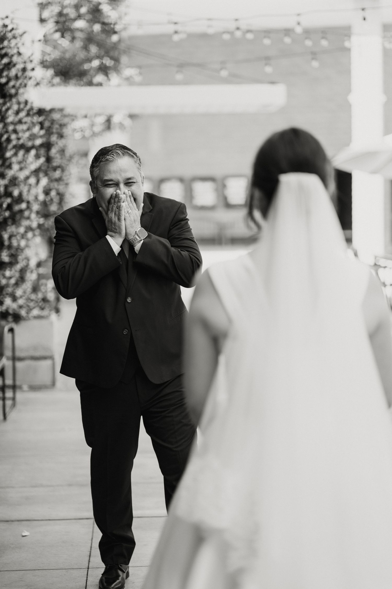 Emotional father covers mouth in awe seeing daughter in wedding dress for first time.