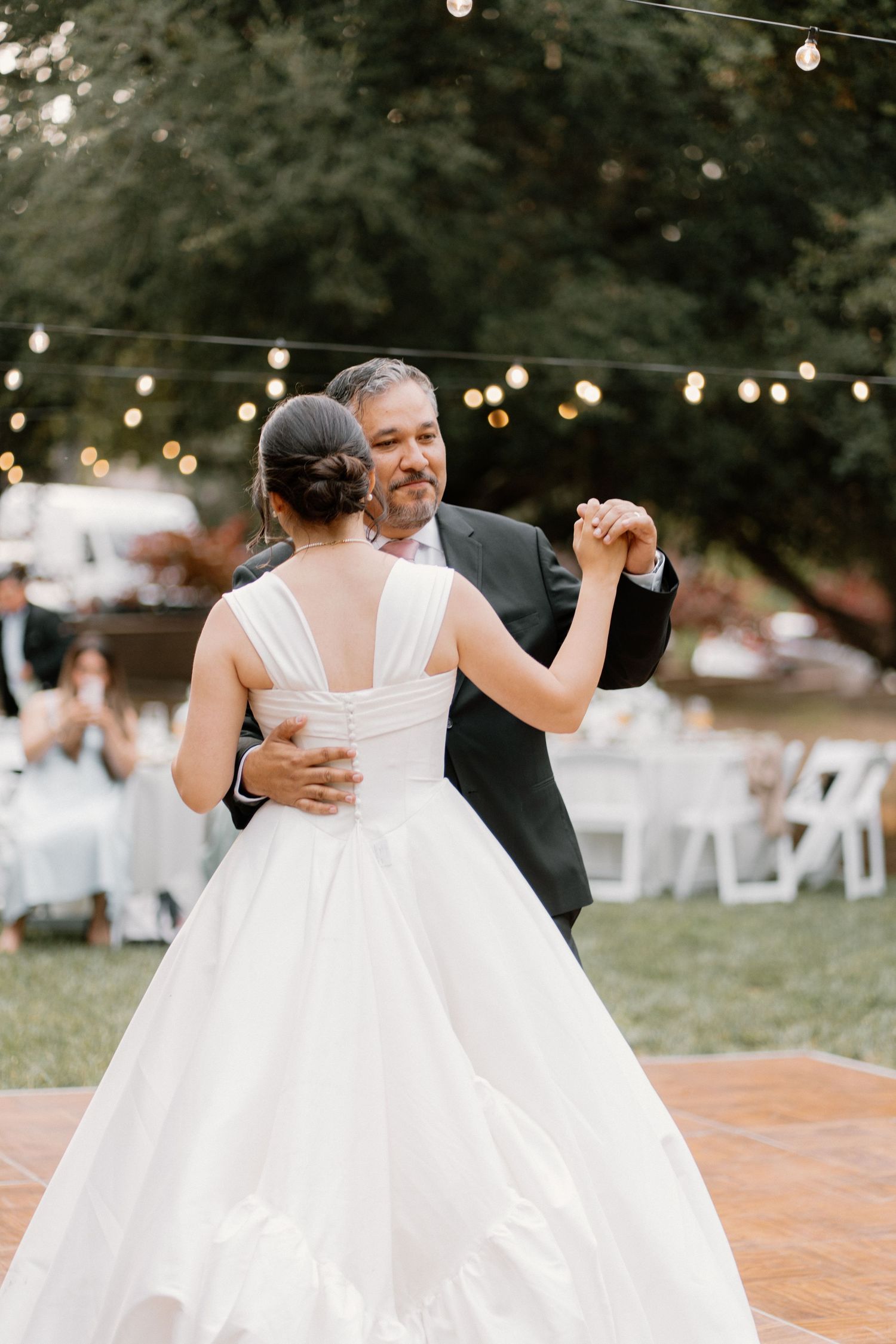 Bride and father share emotional first dance at romantic outdoor wedding reception.
