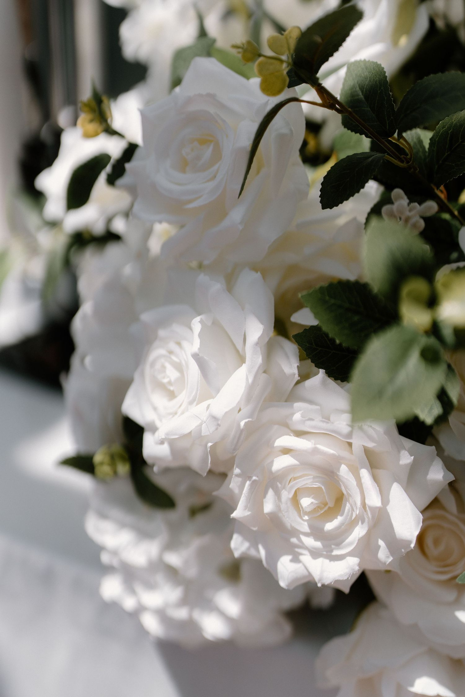 Close-up of elegant white roses with green leaves used as wedding floral decoration arrangement.