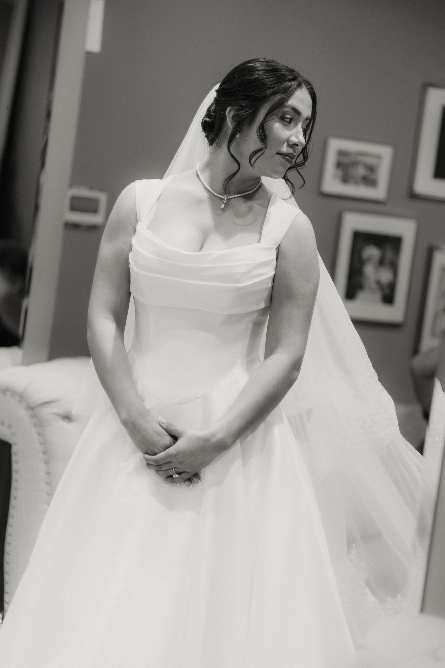 Elegant bride in a white ball gown with veil poses in black and white portrait before her wedding.