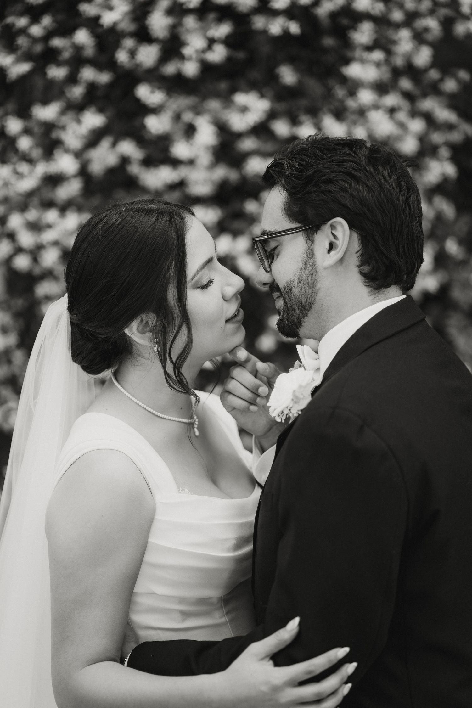 Black and white portrait of bride and groom sharing a romantic almost-kiss on their wedding day.