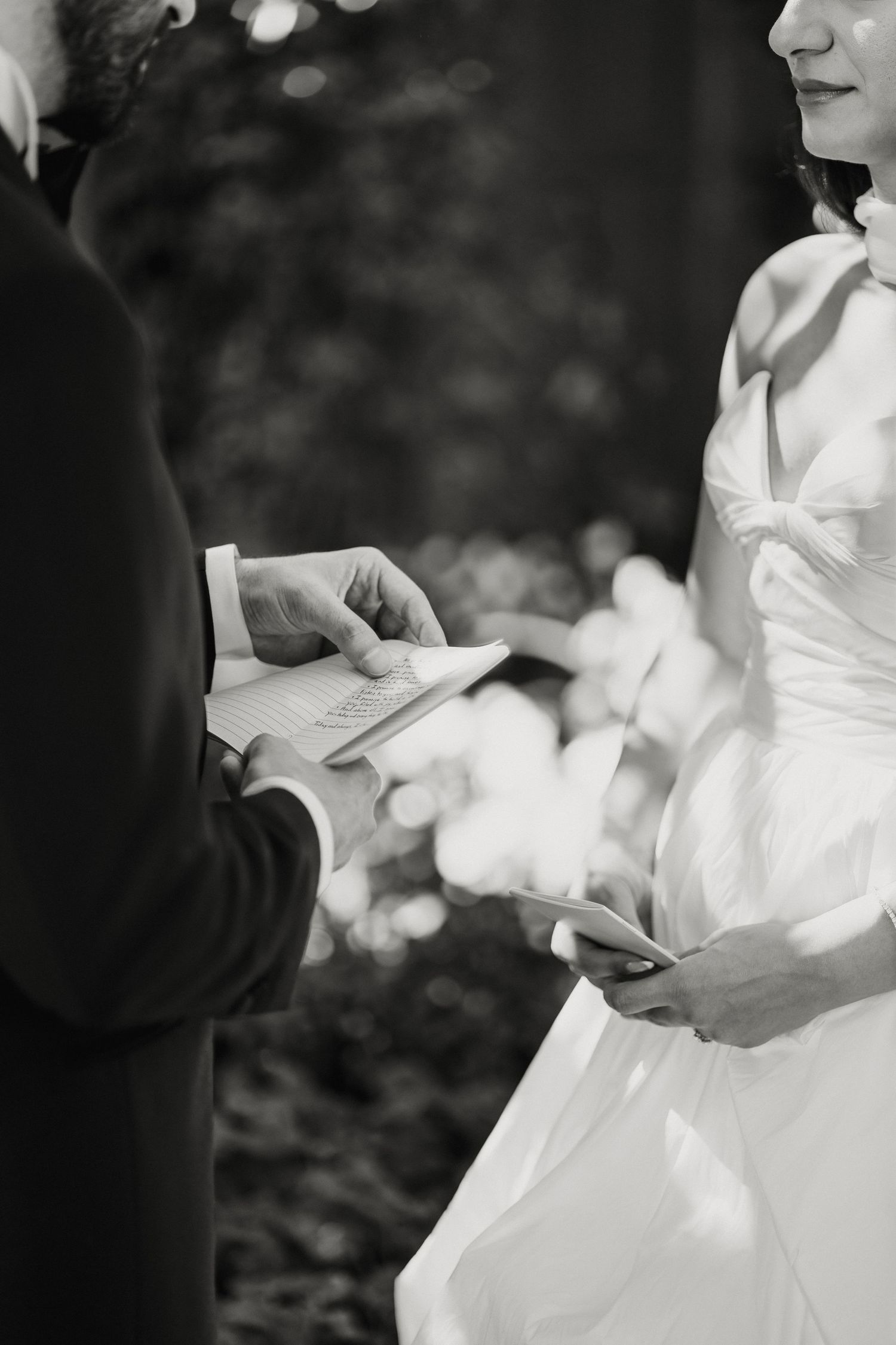 Black and white photo of bride and groom exchanging handwritten vows during wedding ceremony.