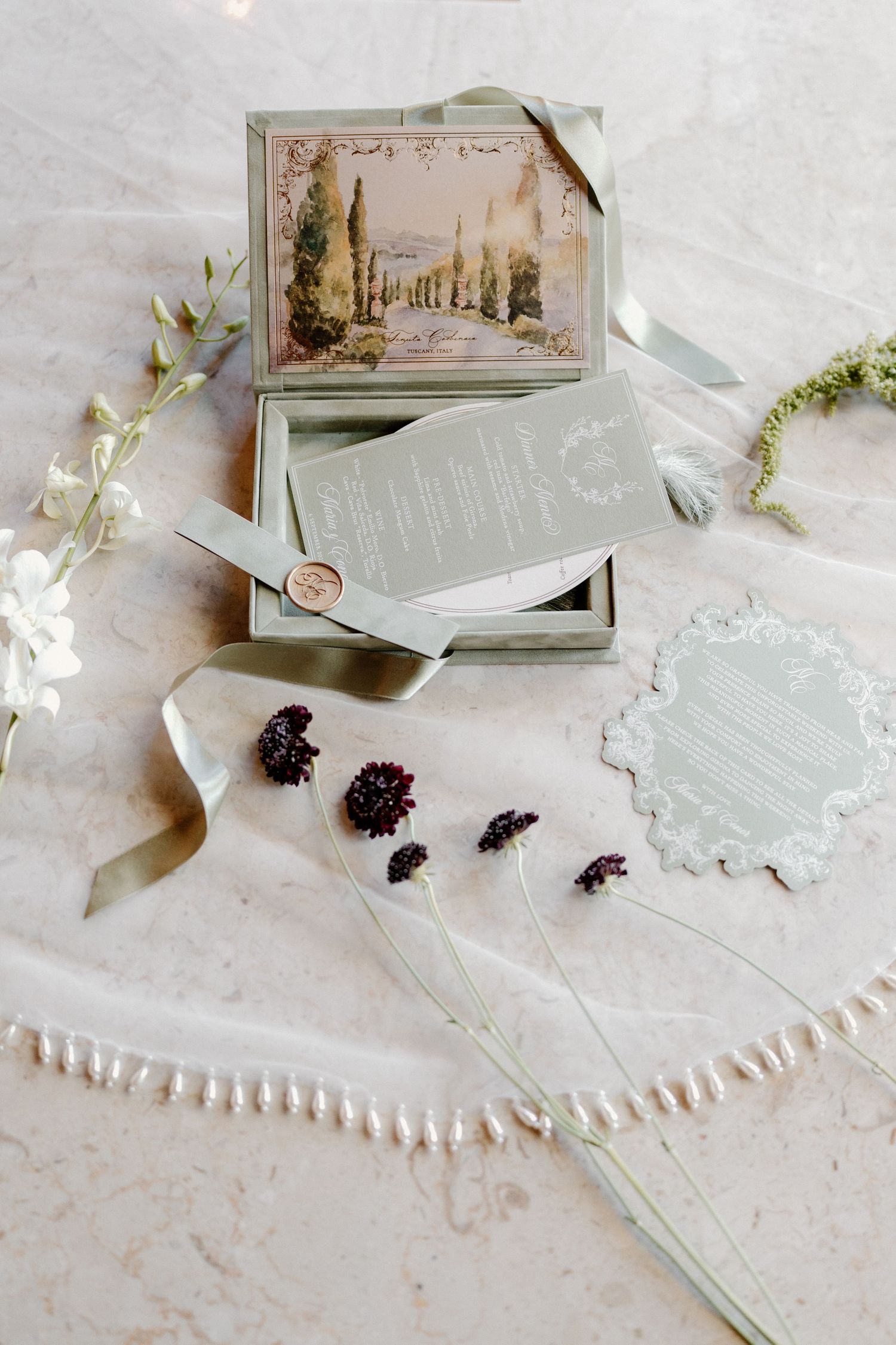 Elegant sage green wedding stationery suite with watercolor landscape artwork and wax seal in box.