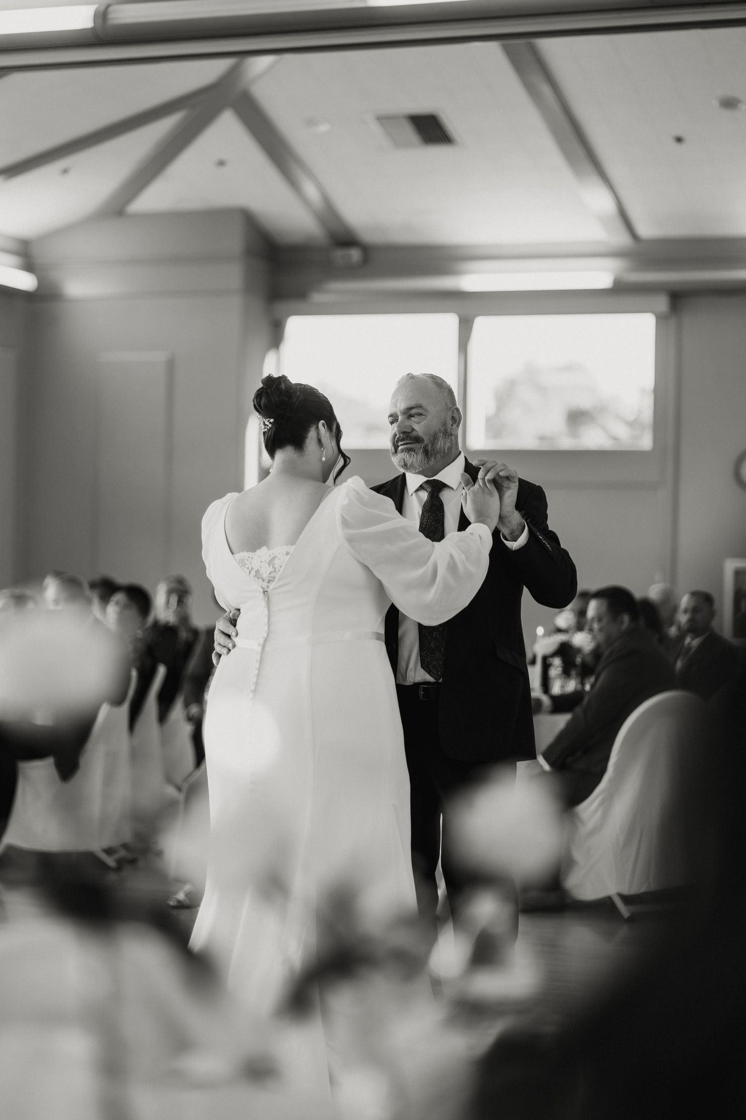 Black and white photo of bride and groom sharing first dance at wedding reception.
