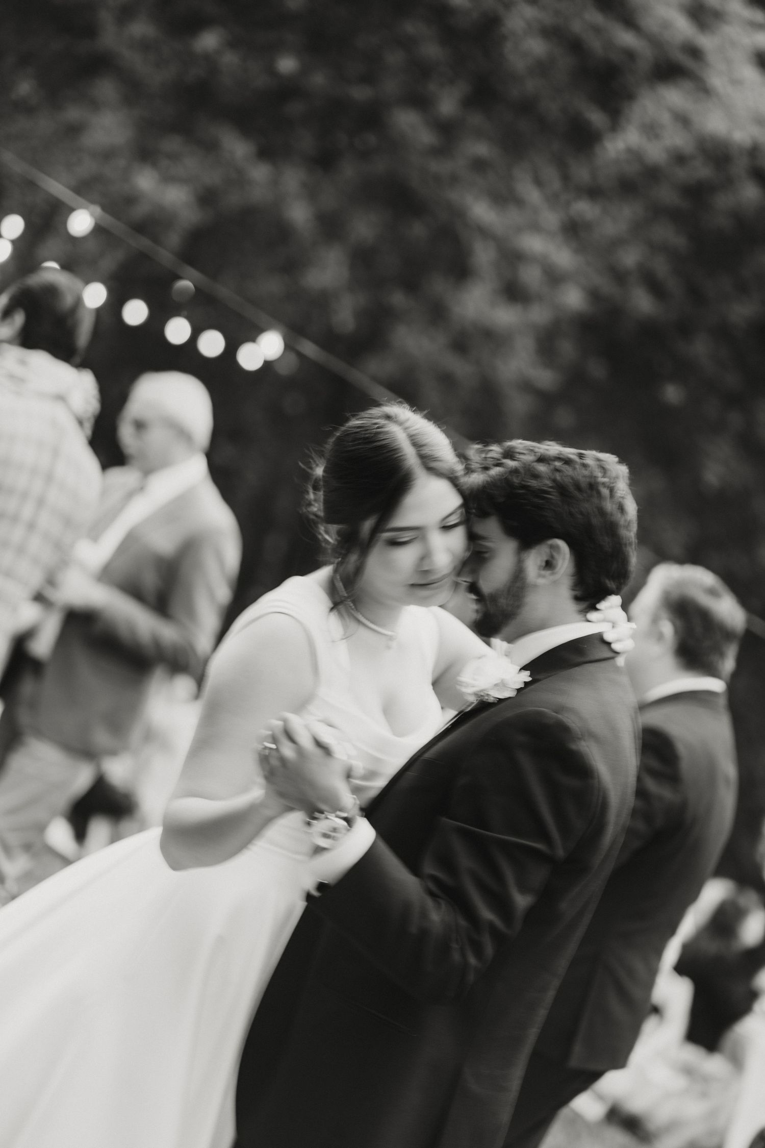 Black and white photo of a bride and groom sharing their first dance at an outdoor wedding reception.