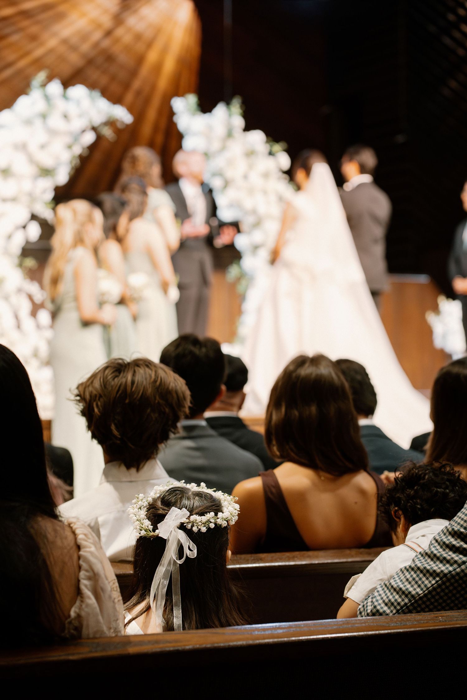 Wedding guests seated in church pews watching the ceremony at a beautifully decorated altar.