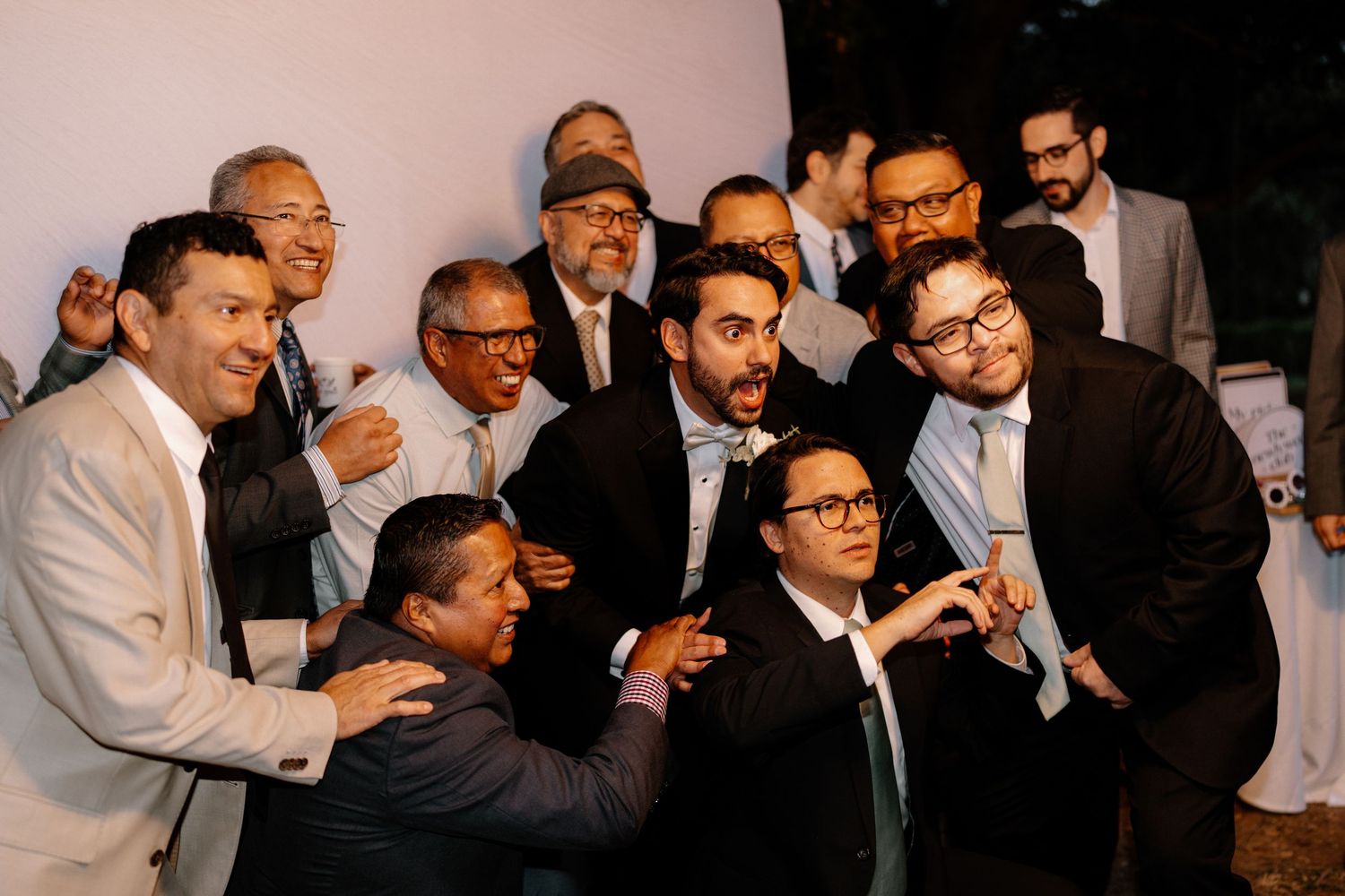Groom and groomsmen pose playfully together for fun group photo at wedding reception.