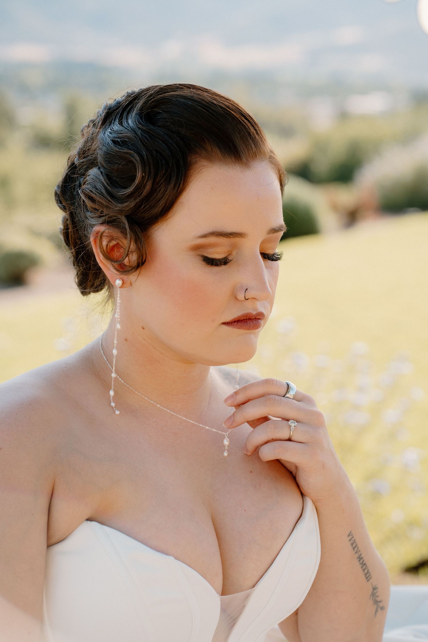 Beautiful bride with vintage finger wave updo, pearl earrings, and nose ring in strapless wedding gown.
