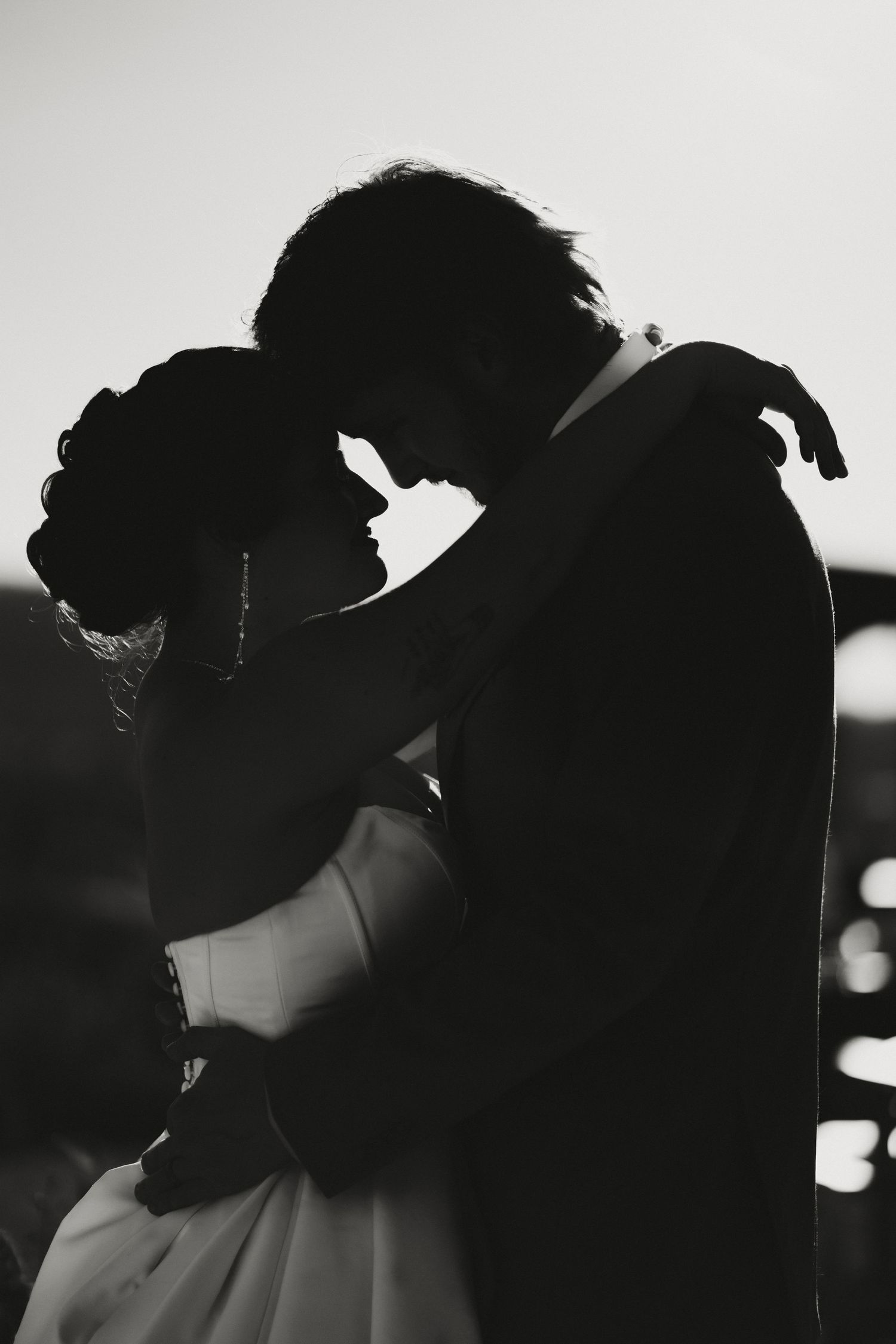 Romantic black and white silhouette of bride and groom embracing closely on their wedding day.