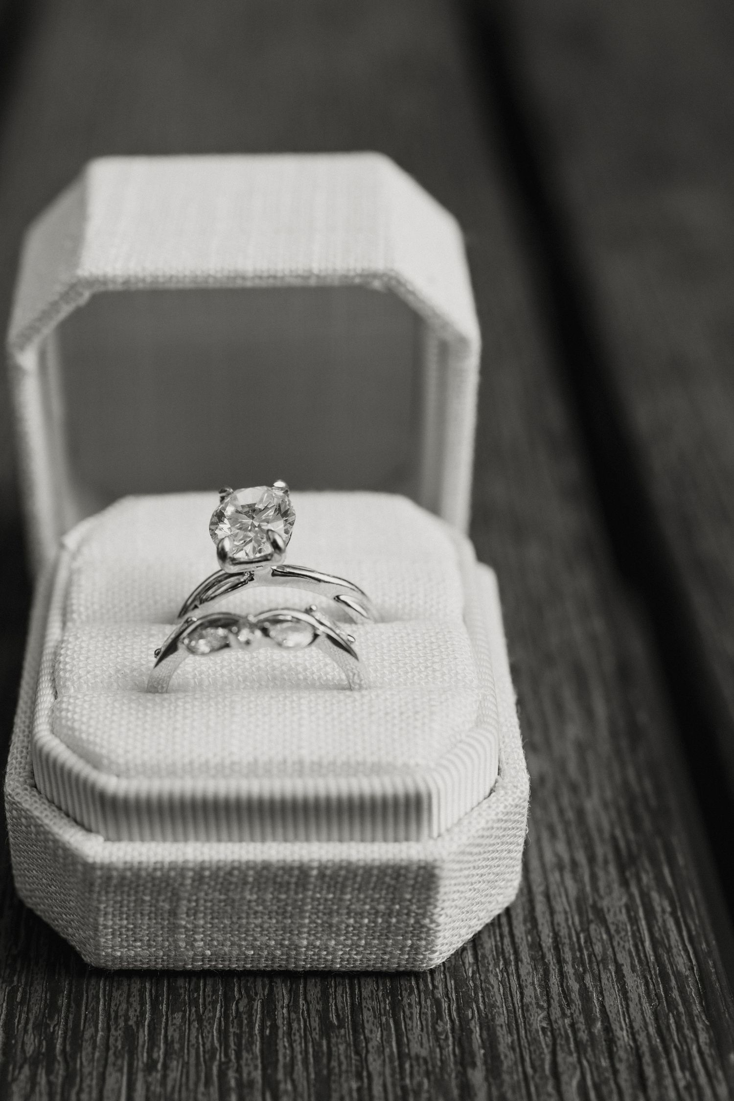 Black and white photo of a diamond solitaire engagement ring with wedding band in a white jewelry box.