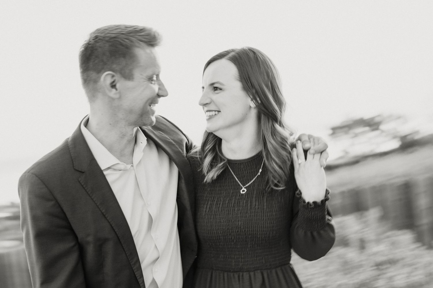Black and white photo of a smiling couple gazing at each other during an engagement session.