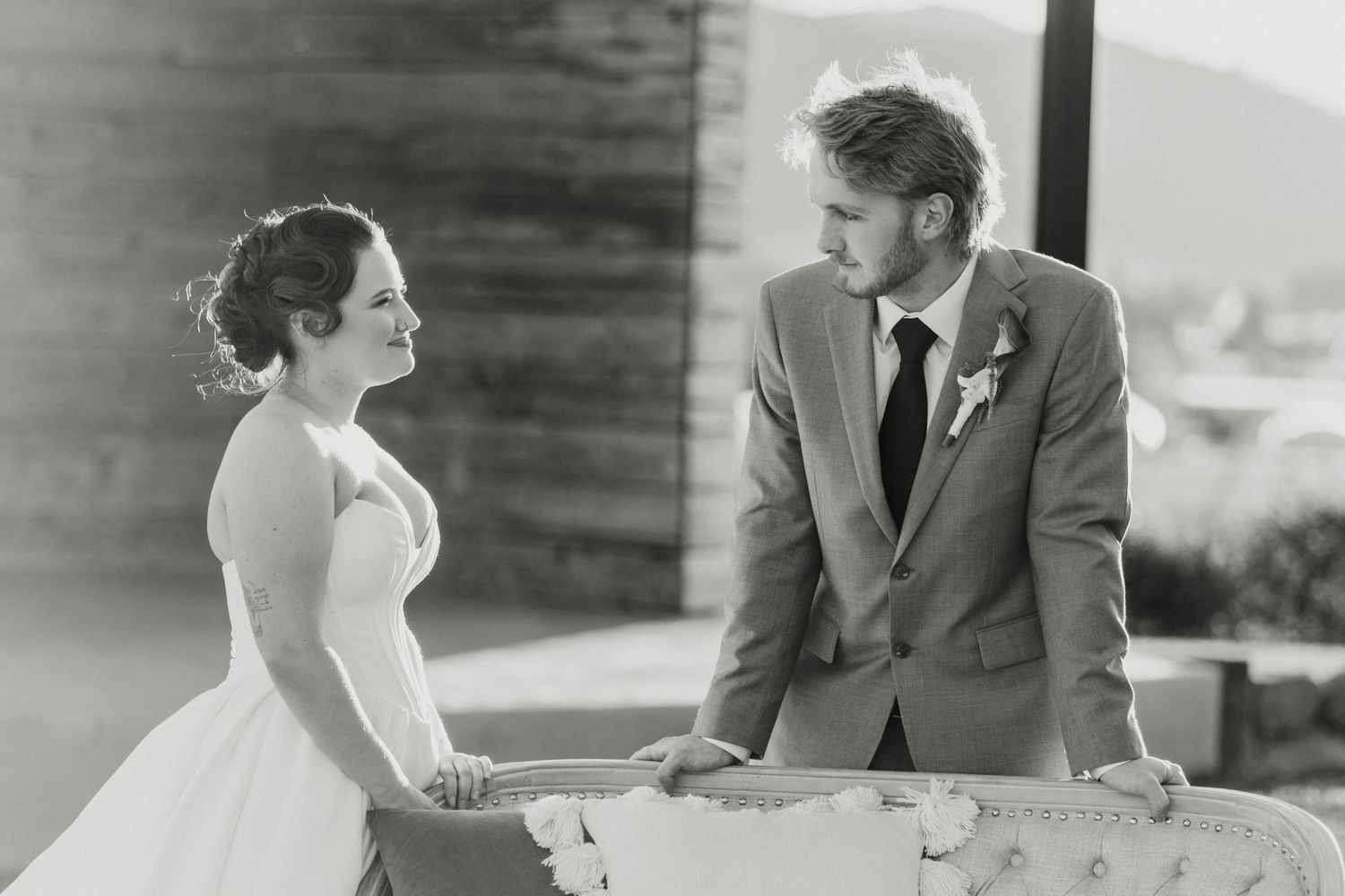 Black and white photo of bride and groom sharing a tender moment at their wedding reception table.