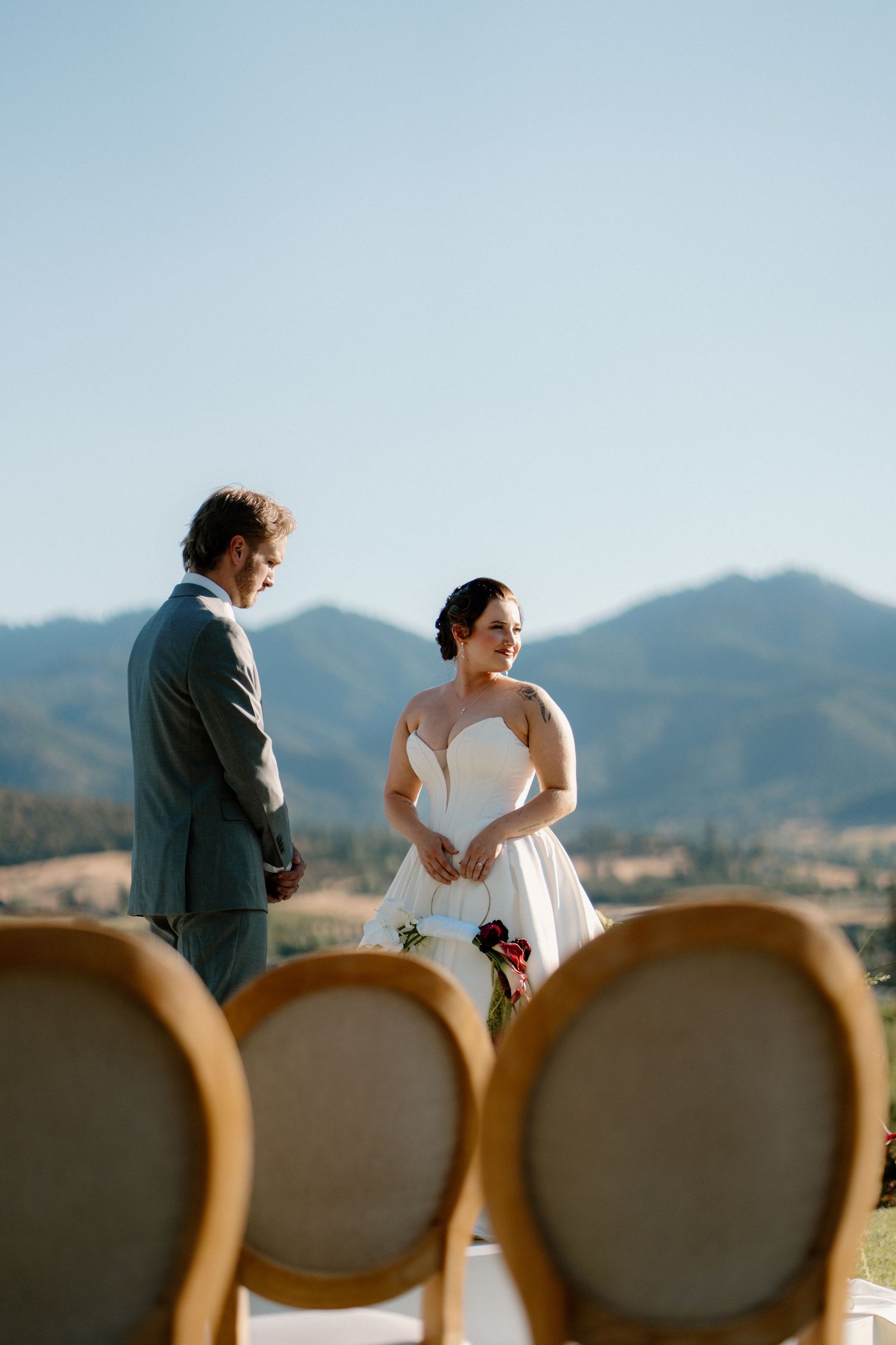 Bride and groom exchange vows outdoors with stunning mountain landscape backdrop on wedding day.