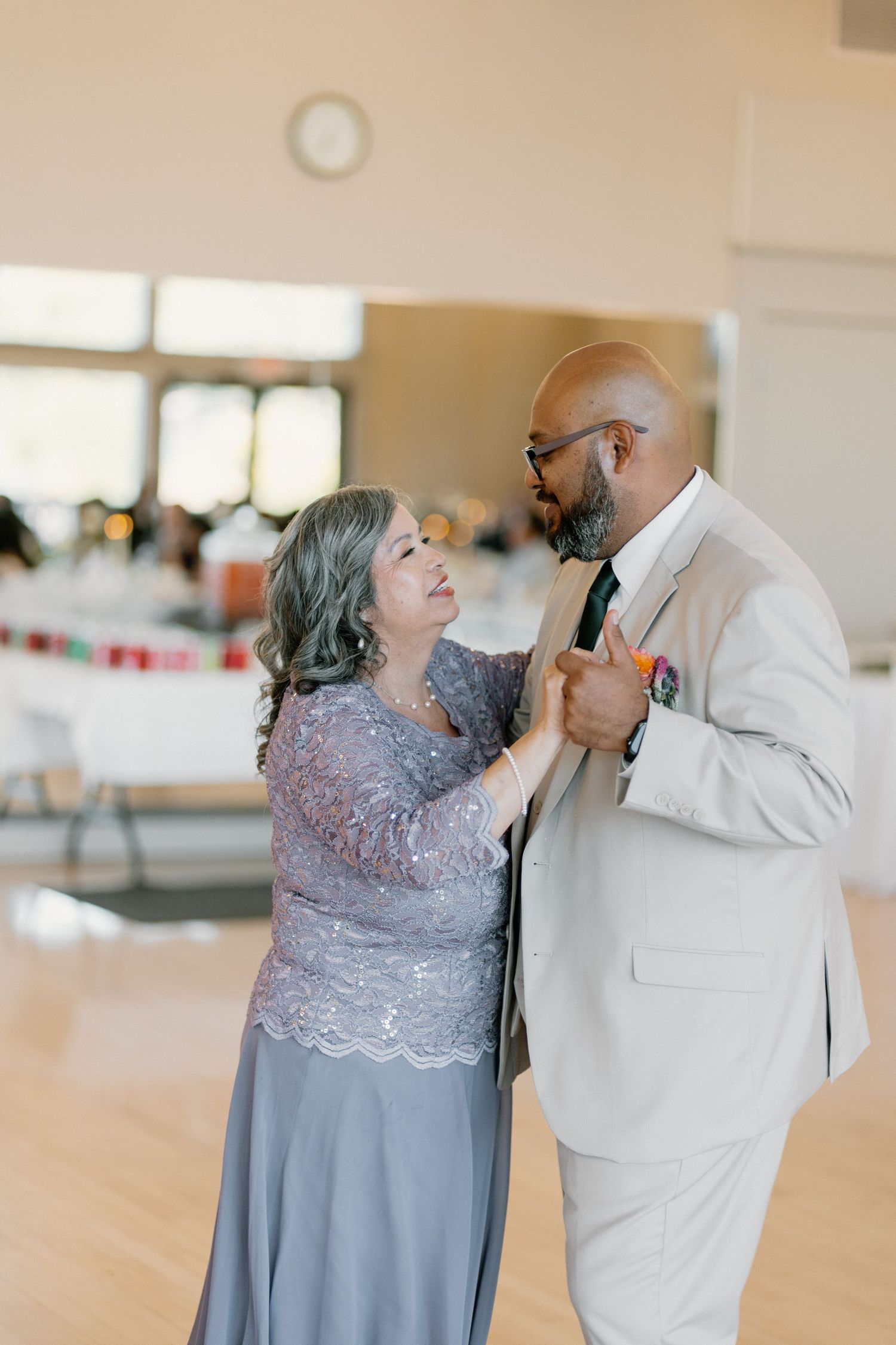 Mother and son share a heartfelt dance at wedding reception in bright decorated hall.