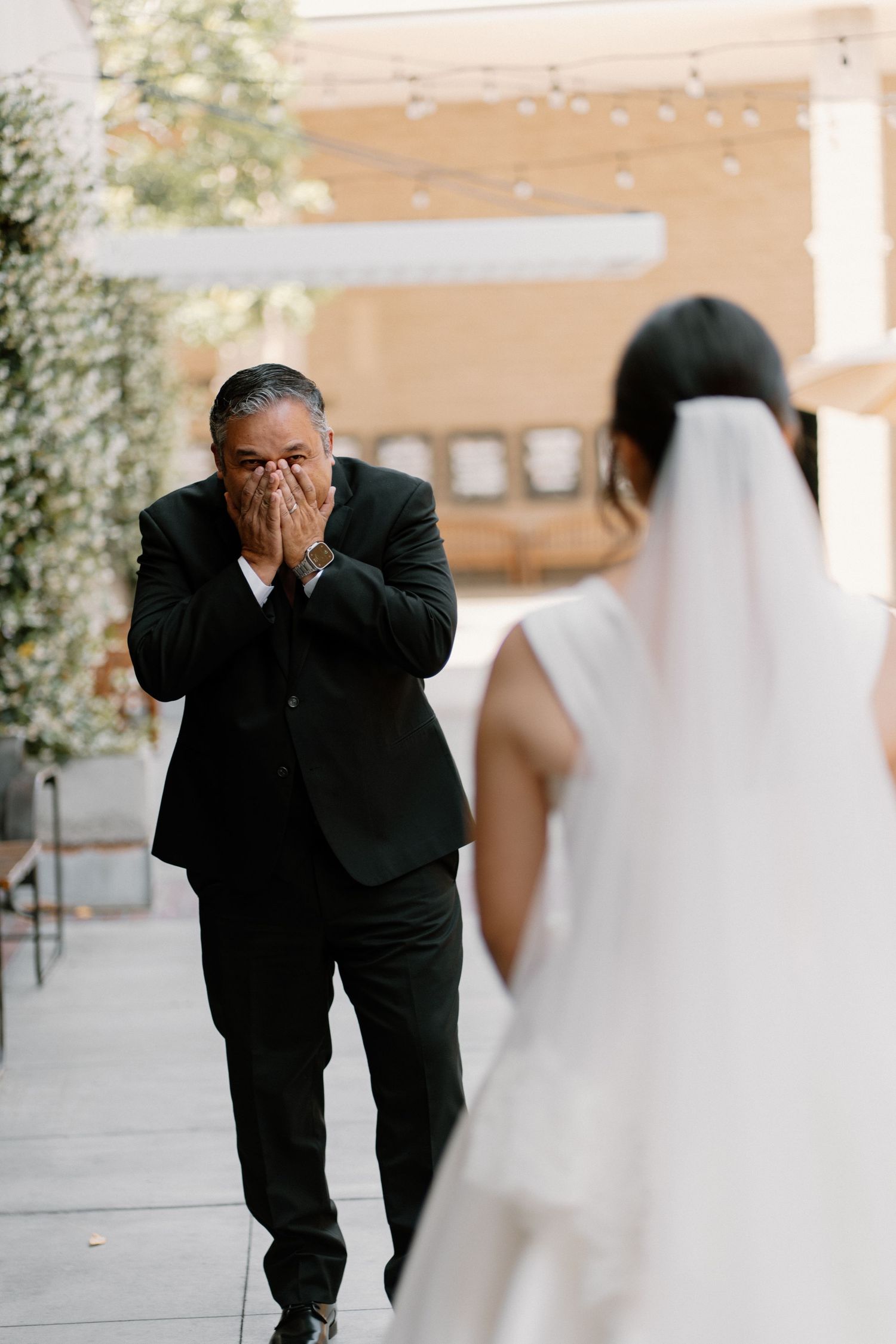 Emotional father covering mouth with hands upon seeing bride daughter for first look before wedding.